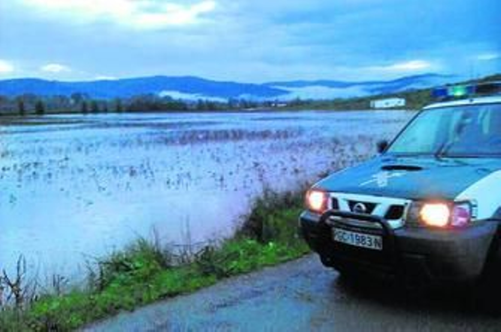 Un vehículo de la Guardia Civil, junto a uno de los ríos desbordados.