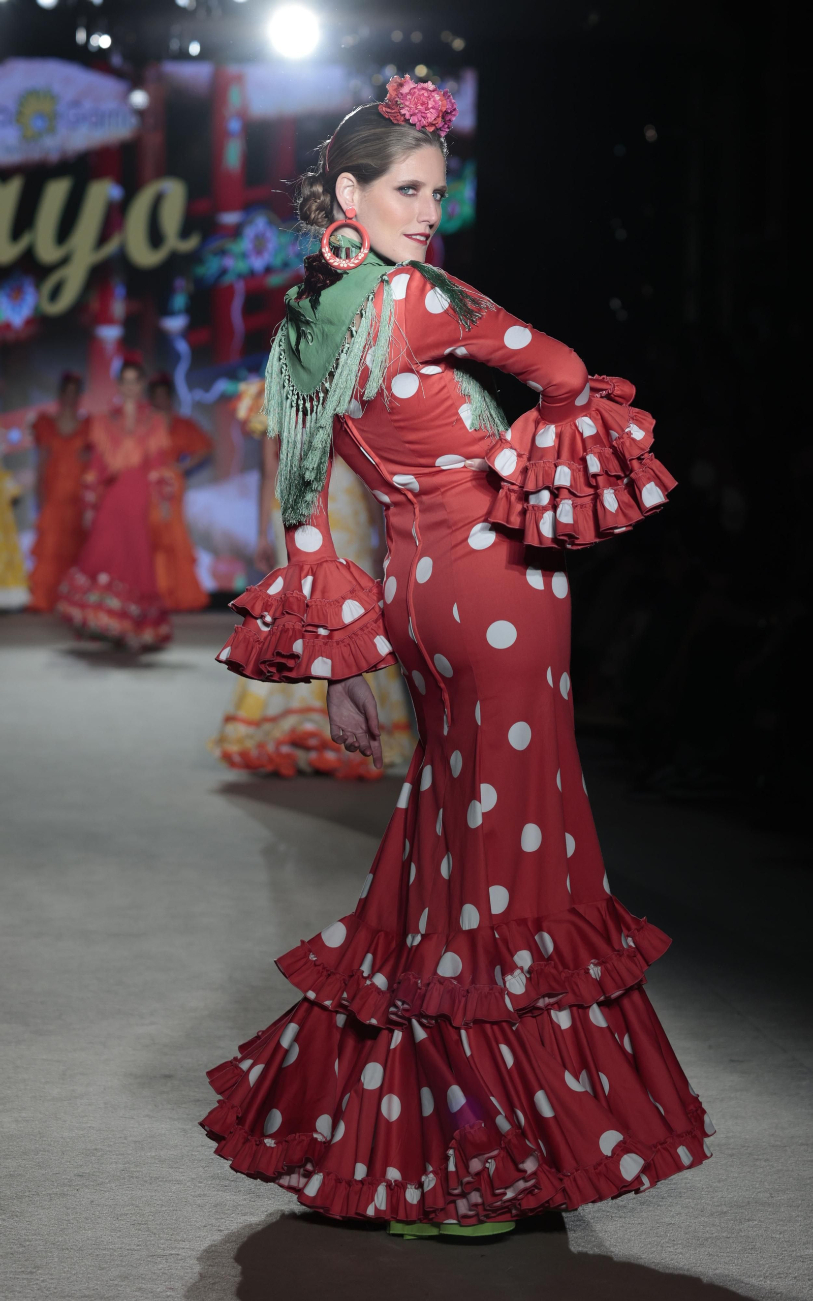 Traje de flamenca rojo combinado con un mantoncillo verde de Pepa Garrido. Traje de flamenca rojo combinado con un mantoncillo verde de Pepa Garrido.