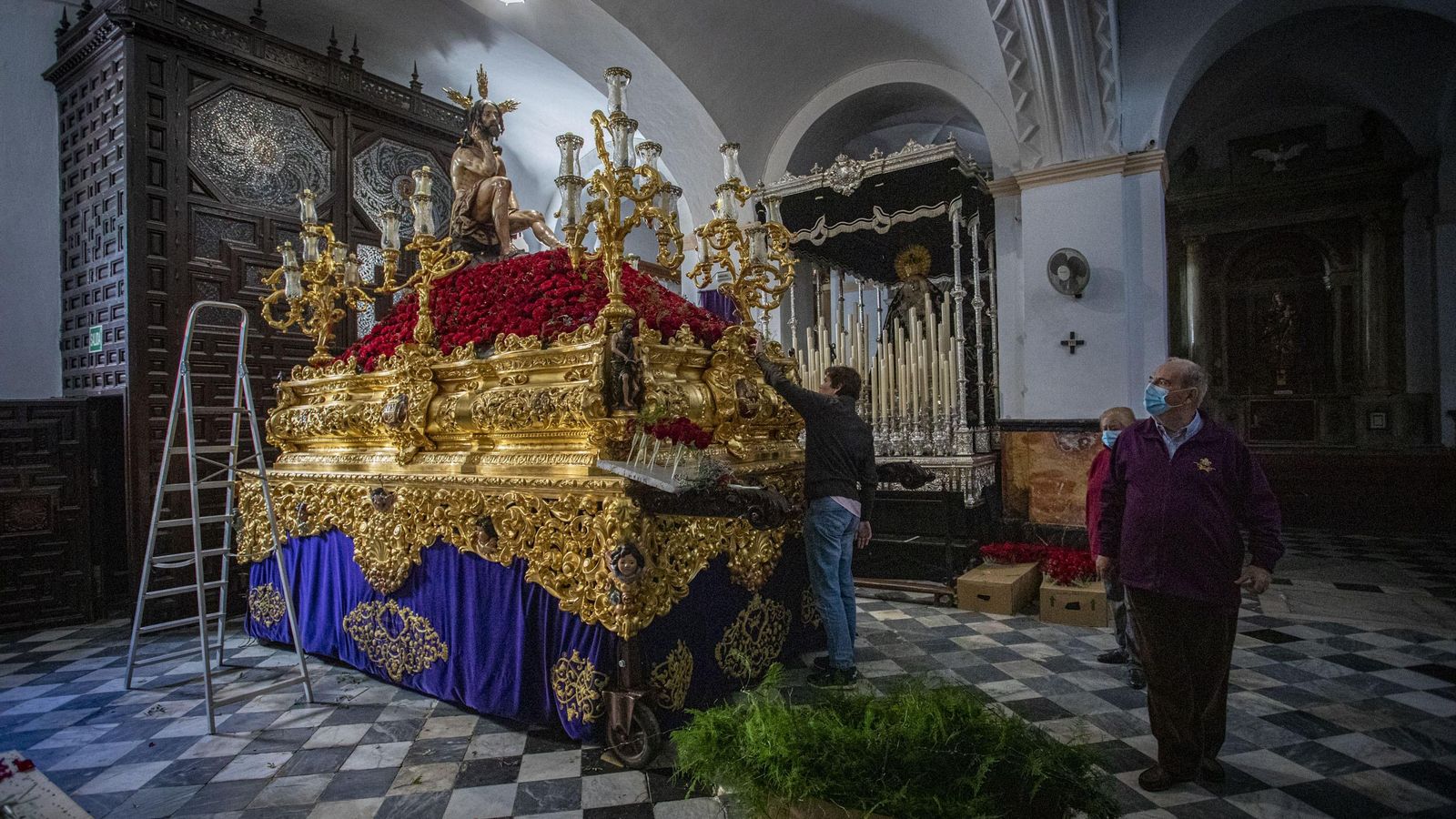 Un hermano coloca el monte de flores del paso de Humildad y Paciencia.