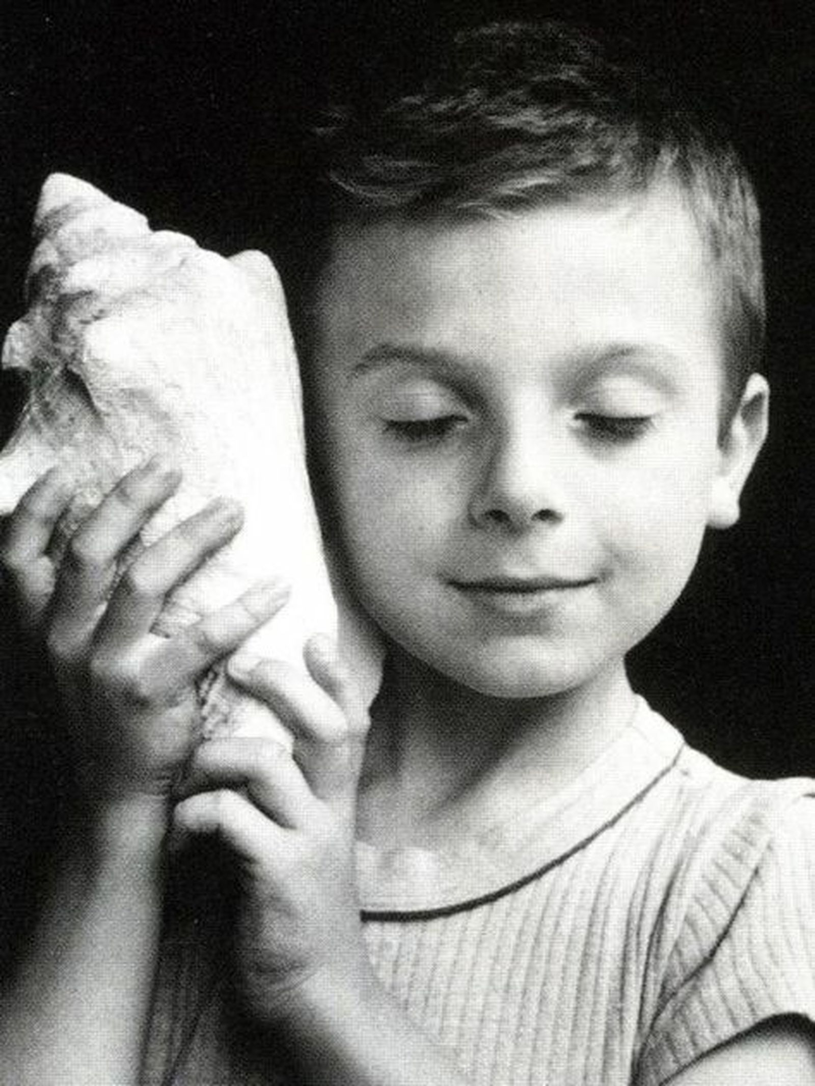 Niño escuchando por una caracola.
