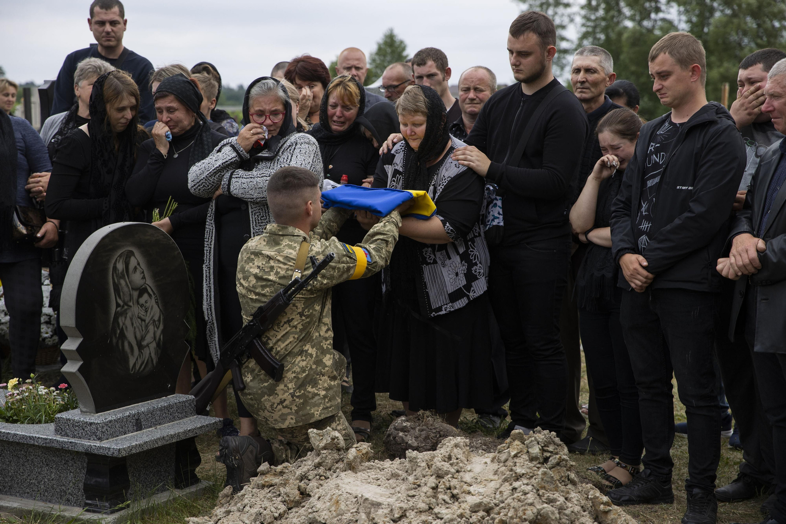 un soldado que entrega una bandera a la madre de un compañero en Novyi Vytkiv .