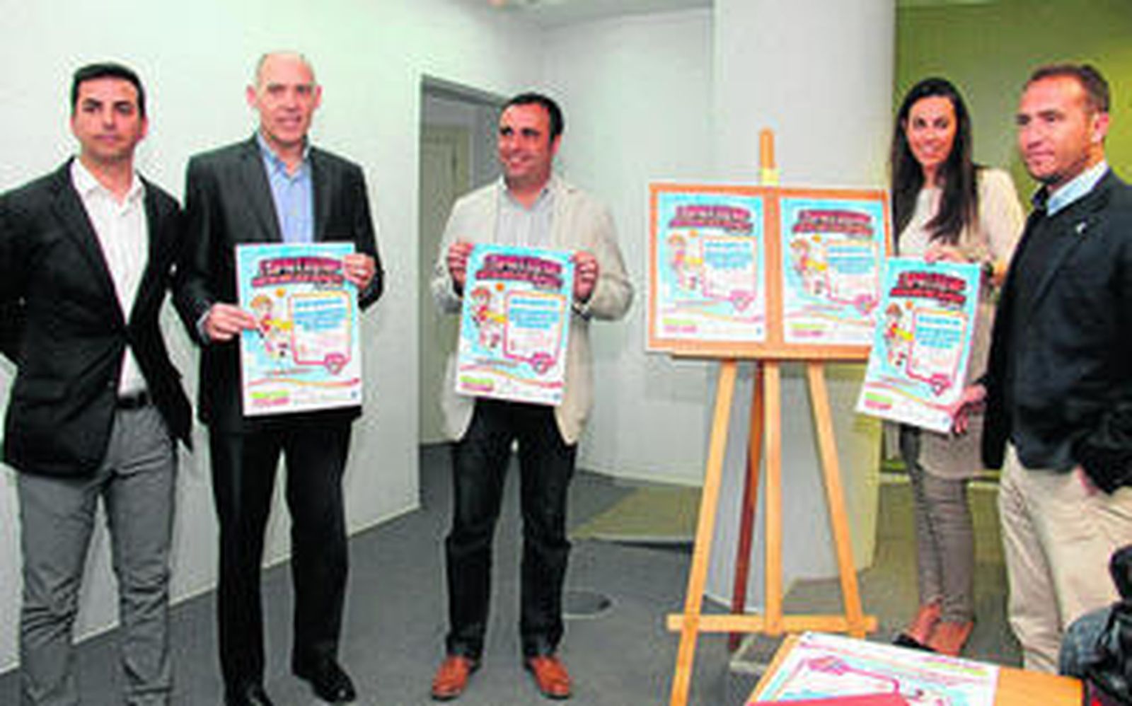 Los organizadores posan con el cartel del evento una vez concluido el acto de presentación.