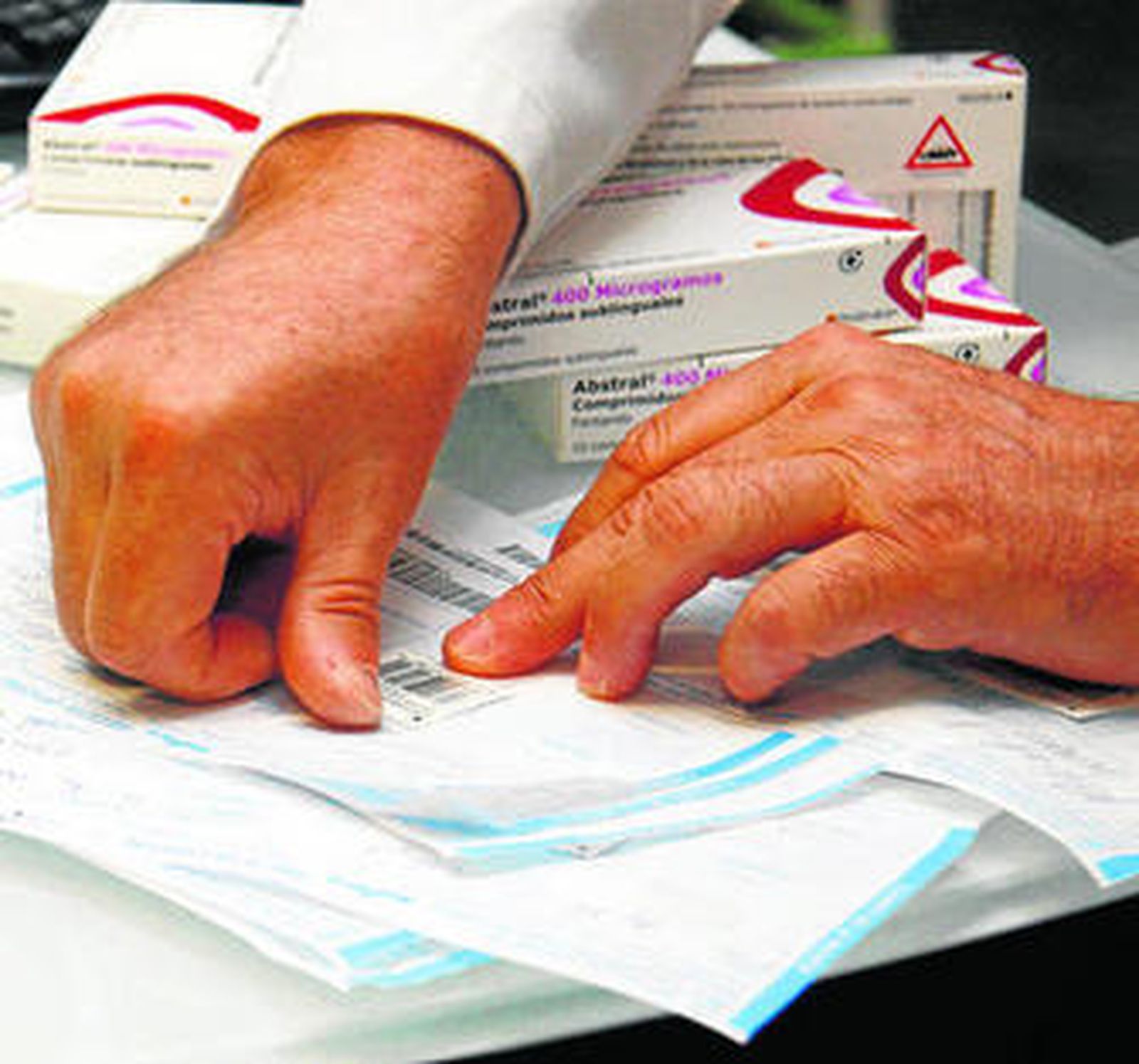 Un boticario pega el precinto en una receta.