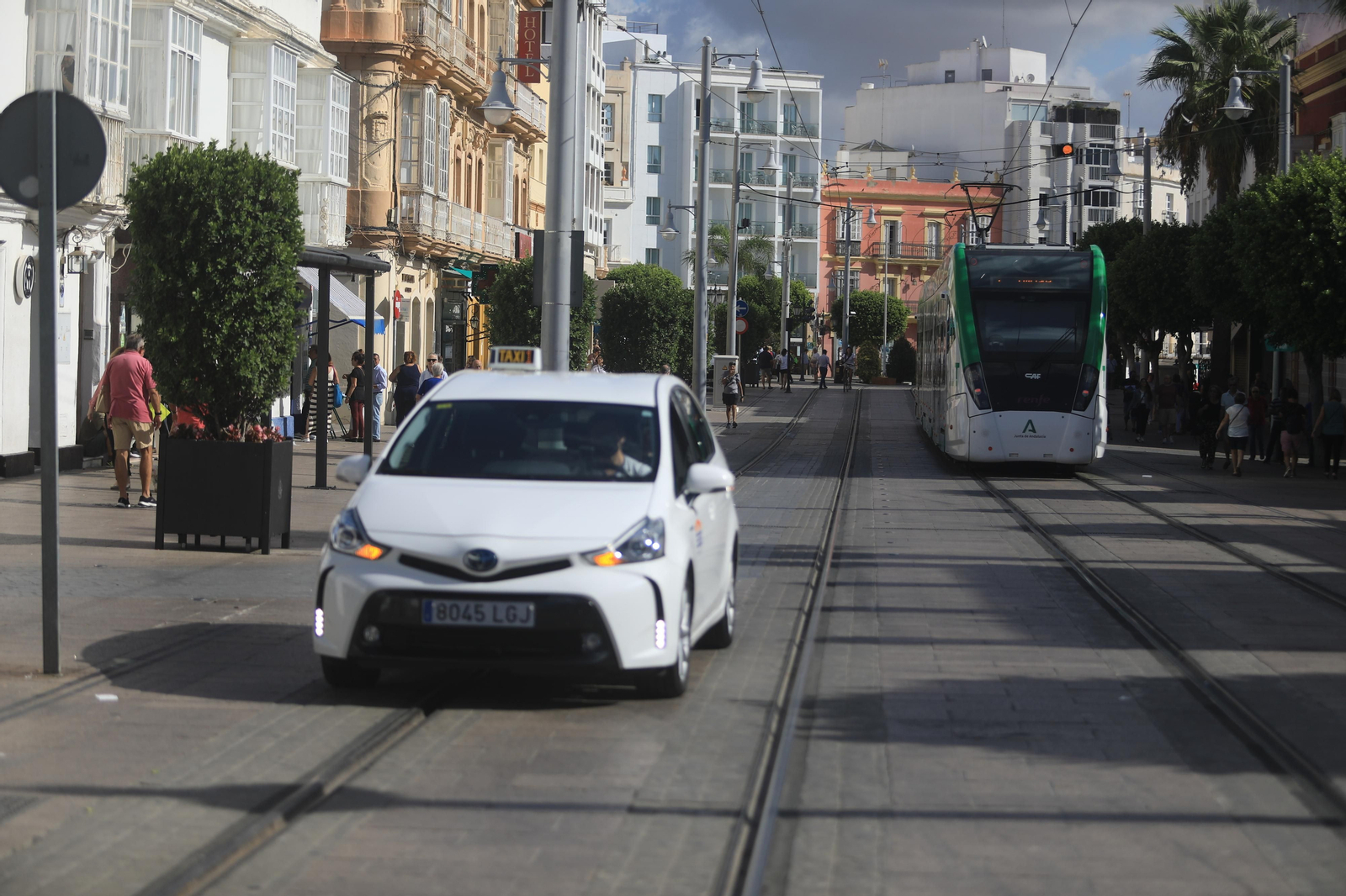 Un taxi recorre la calle Real con el tranvía circulando cerca.