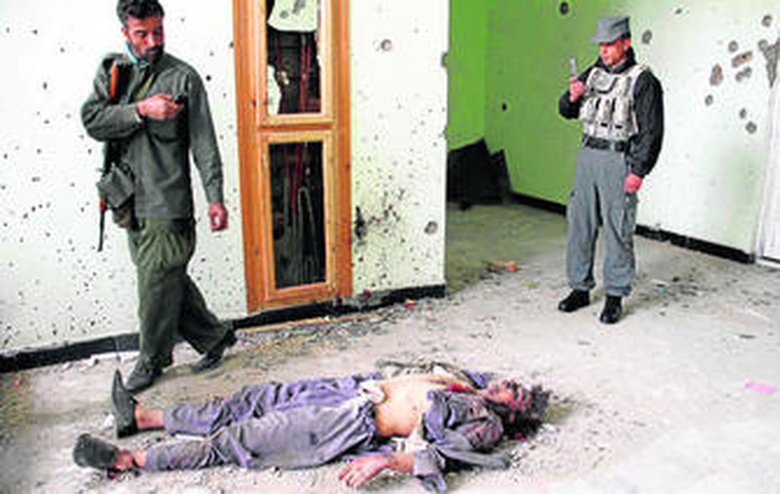 Agentes de las fuerzas de seguridad afganas comprueban el cadáver de un supuesto talibán.