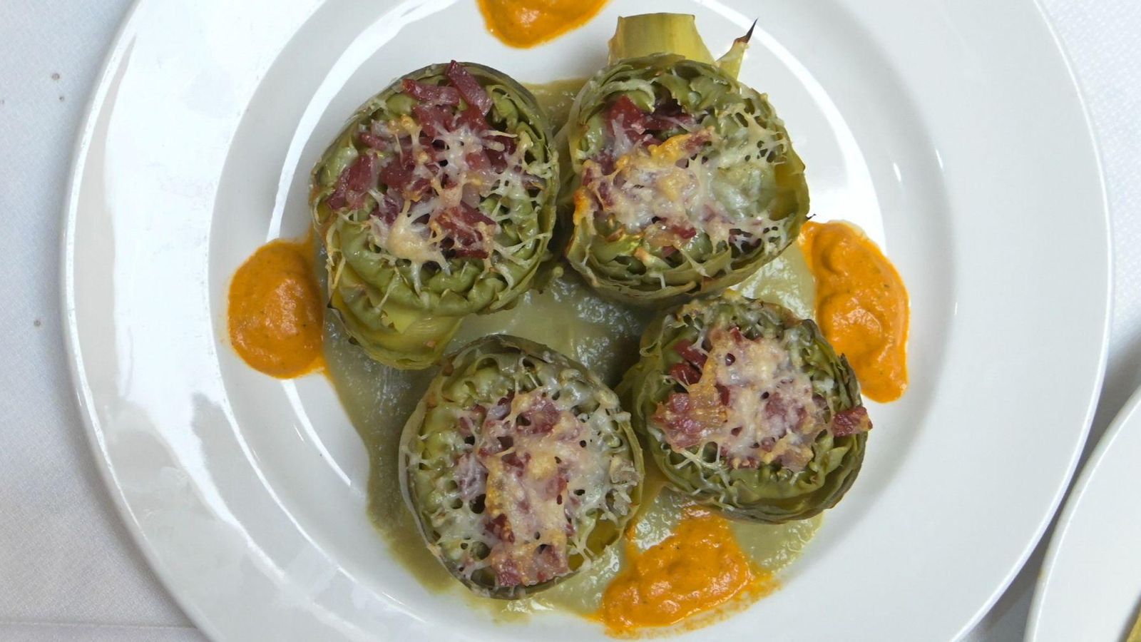 Flor de alcachofa rellena con jamón ibérico y gratinado de parmesano con salsa romescu