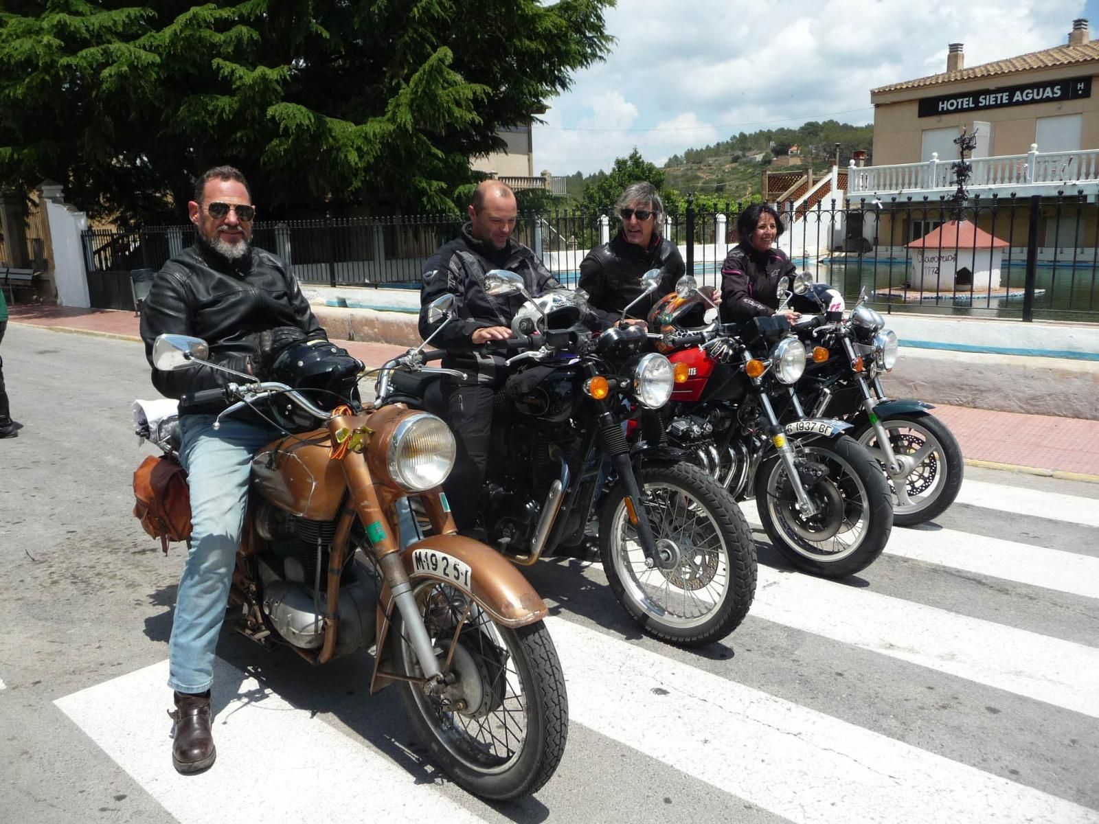 Un cuarteto de veteranos moteros en un paso de peatones con sus monturas