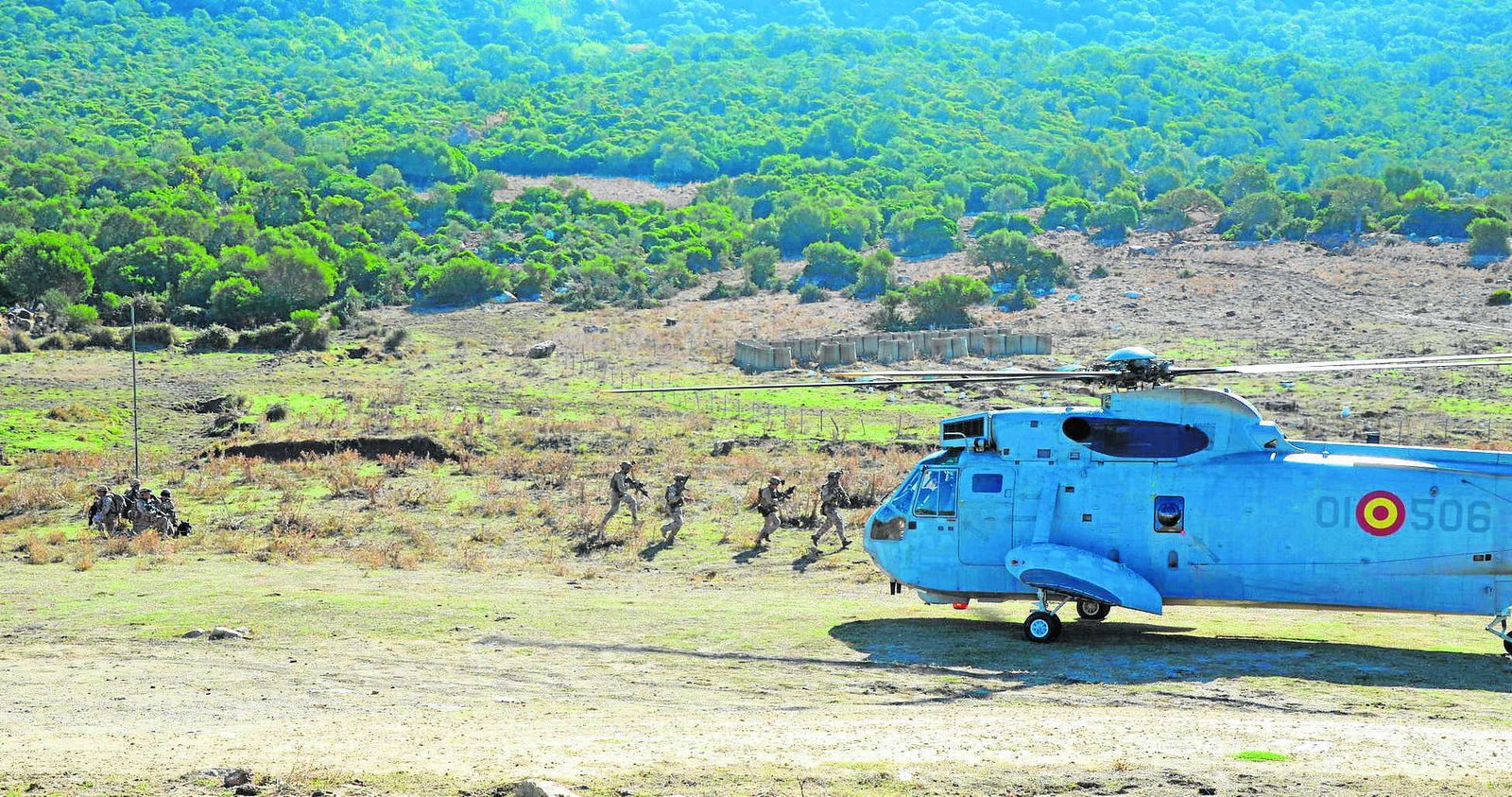 Extracción del equipo de la Fuerza Naval de Guerra Especial tras incursionar contra un objetivo. Un grupo evacua a un herido al helicóptero, mientras sus compañeros agachados les cubren (lupa).