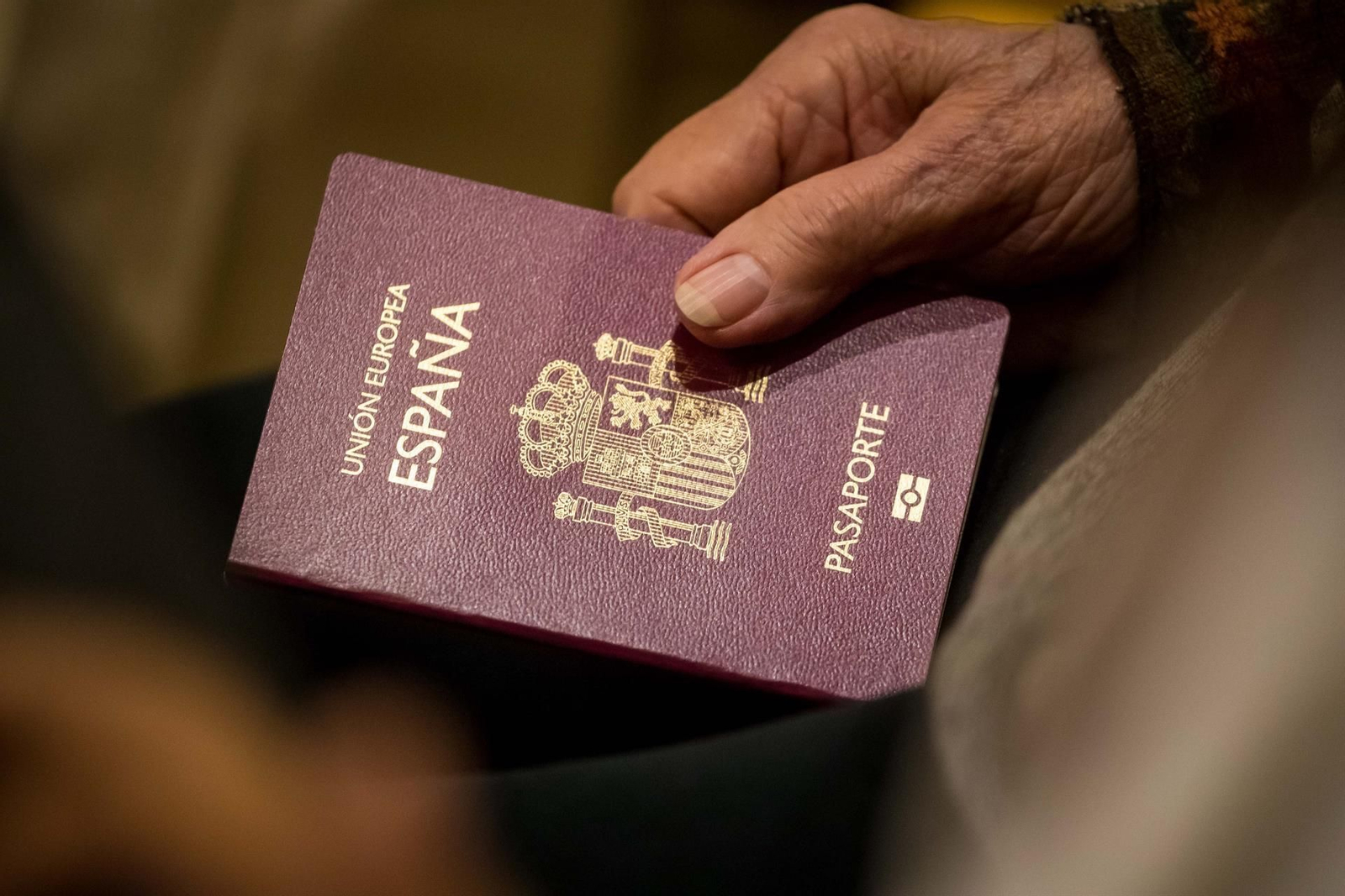 Una persona sosteniendo un pasaporte de España Una persona sosteniendo un pasaporte de España