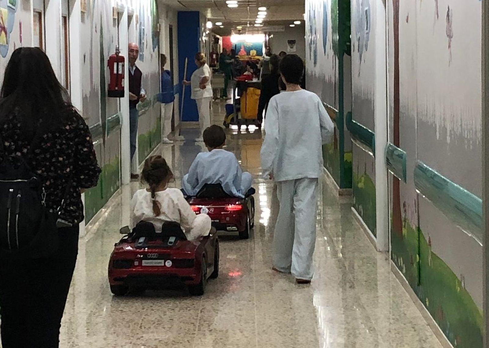 Dos menores por un pasillo del hospital con los coches donados.