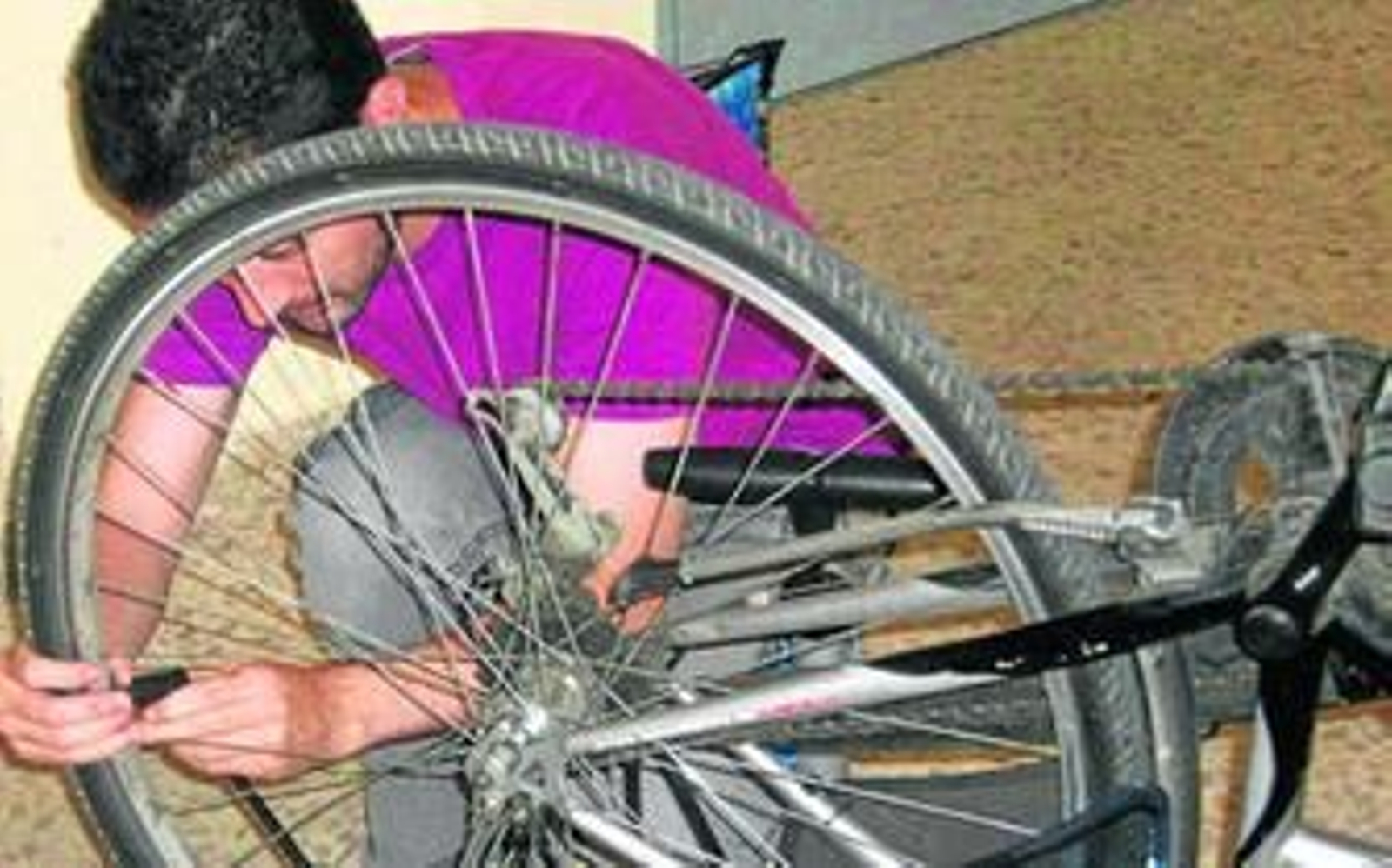 Un joven arregla la bicicleta de otro participante en el Banco del Tiempo.