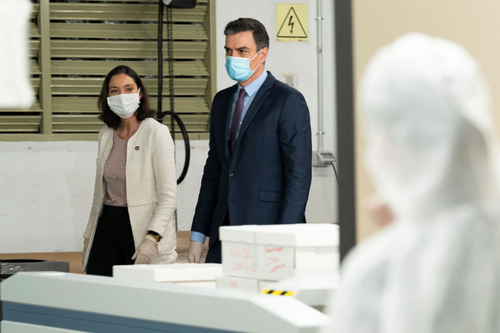 Pedro  Sánchez  y la ministra de Industria, Reyes Maroto, usando mascarilla durante la visita a unos talleres de confección.