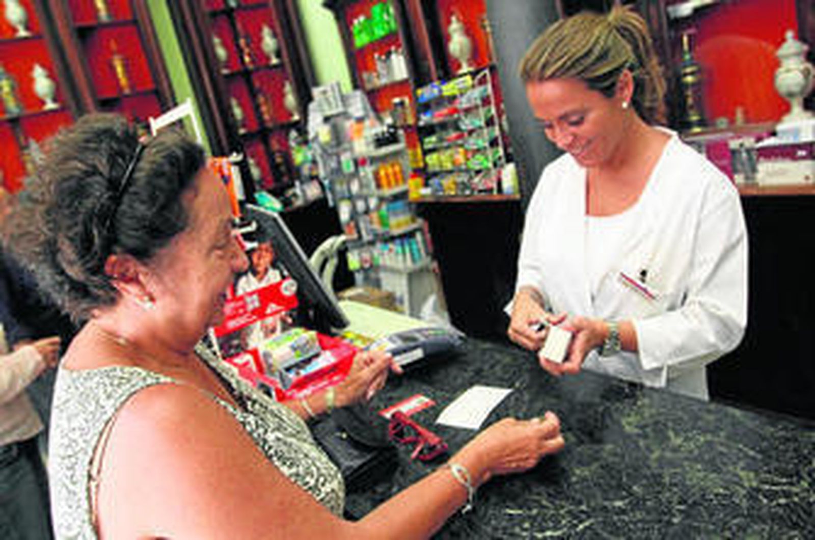 Una farmacéutica atiende a su clientela habitual.