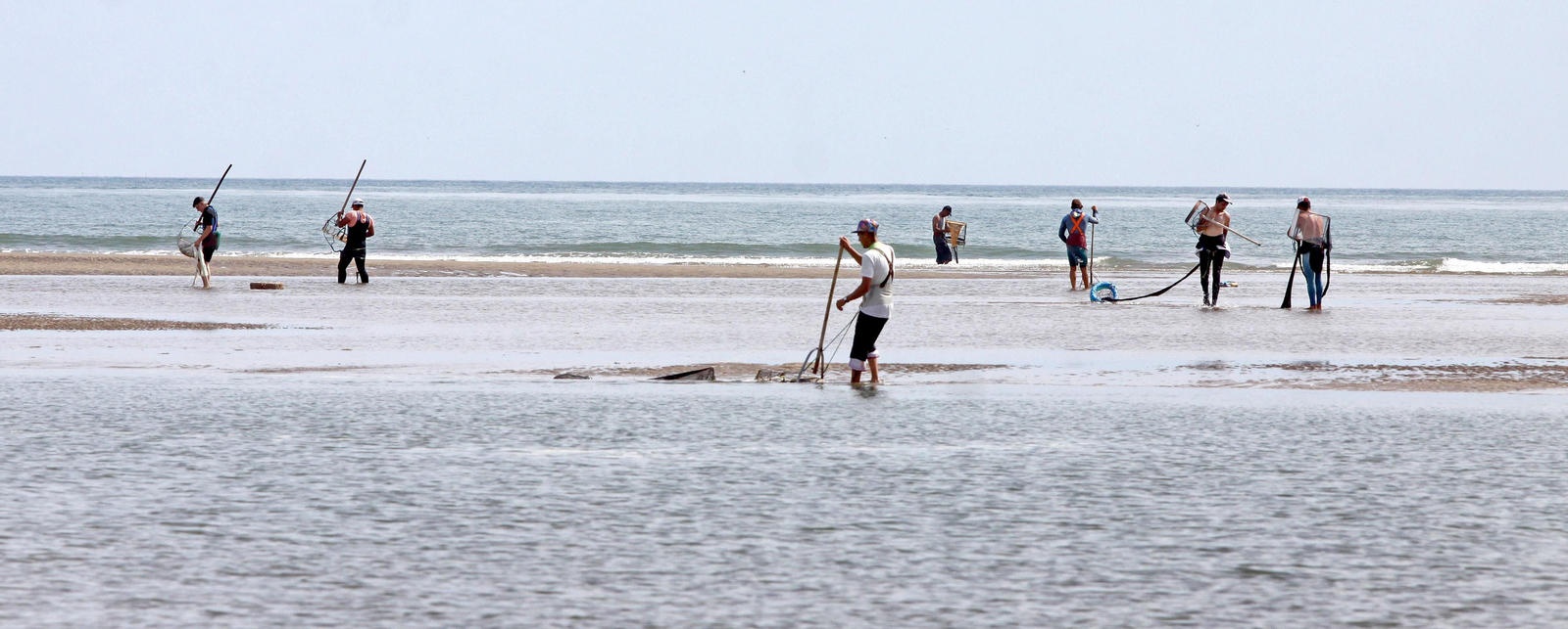 Mariscadores de a pie en pleno trabajo de captura de coquina.