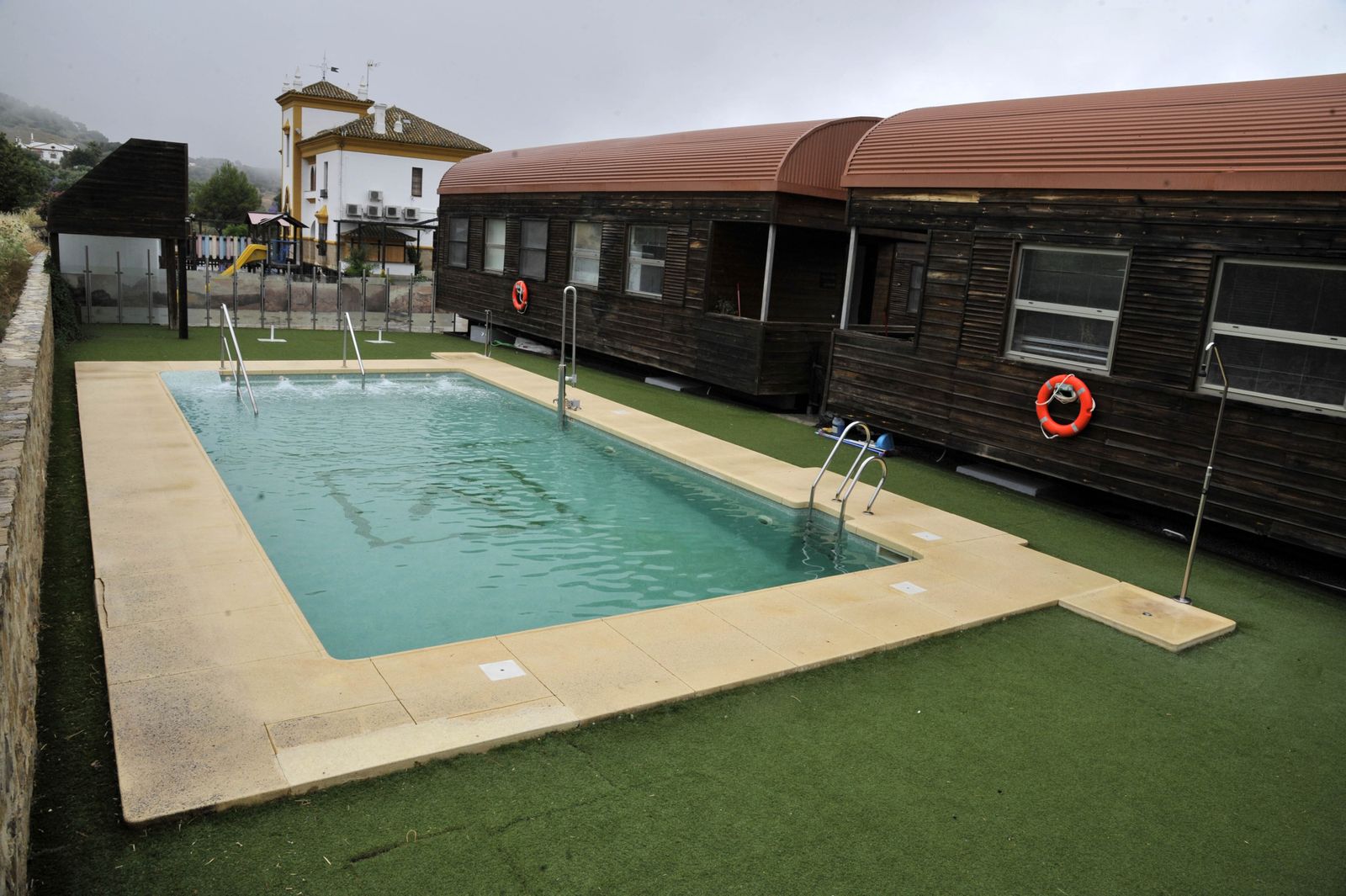 Vista lateral de dos de las cuatro casas-vagón que hay junto a la antigua estación de tren de Olvera. En primer plano, la piscina de agua salada.