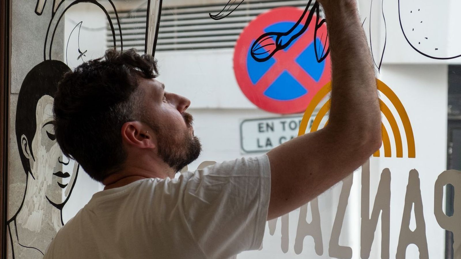 Uno de los artistas interviene el escaparate de Panzamorena.