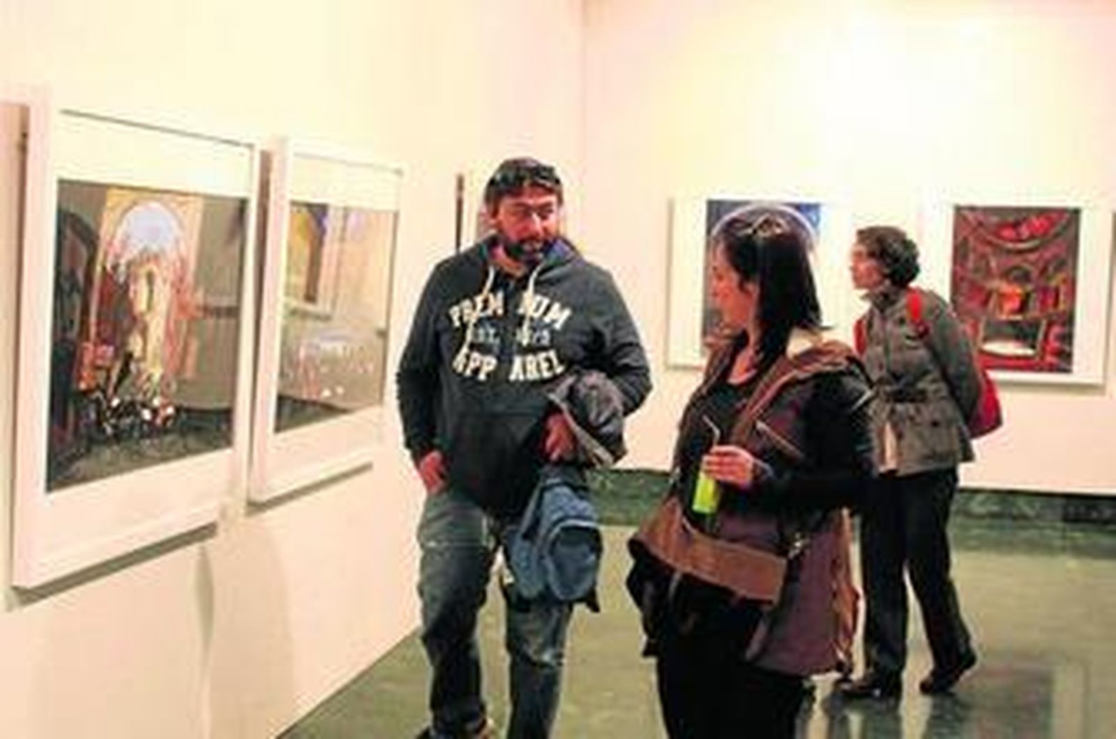 Un grupo de personas mira algunas de las obras de la exposición.