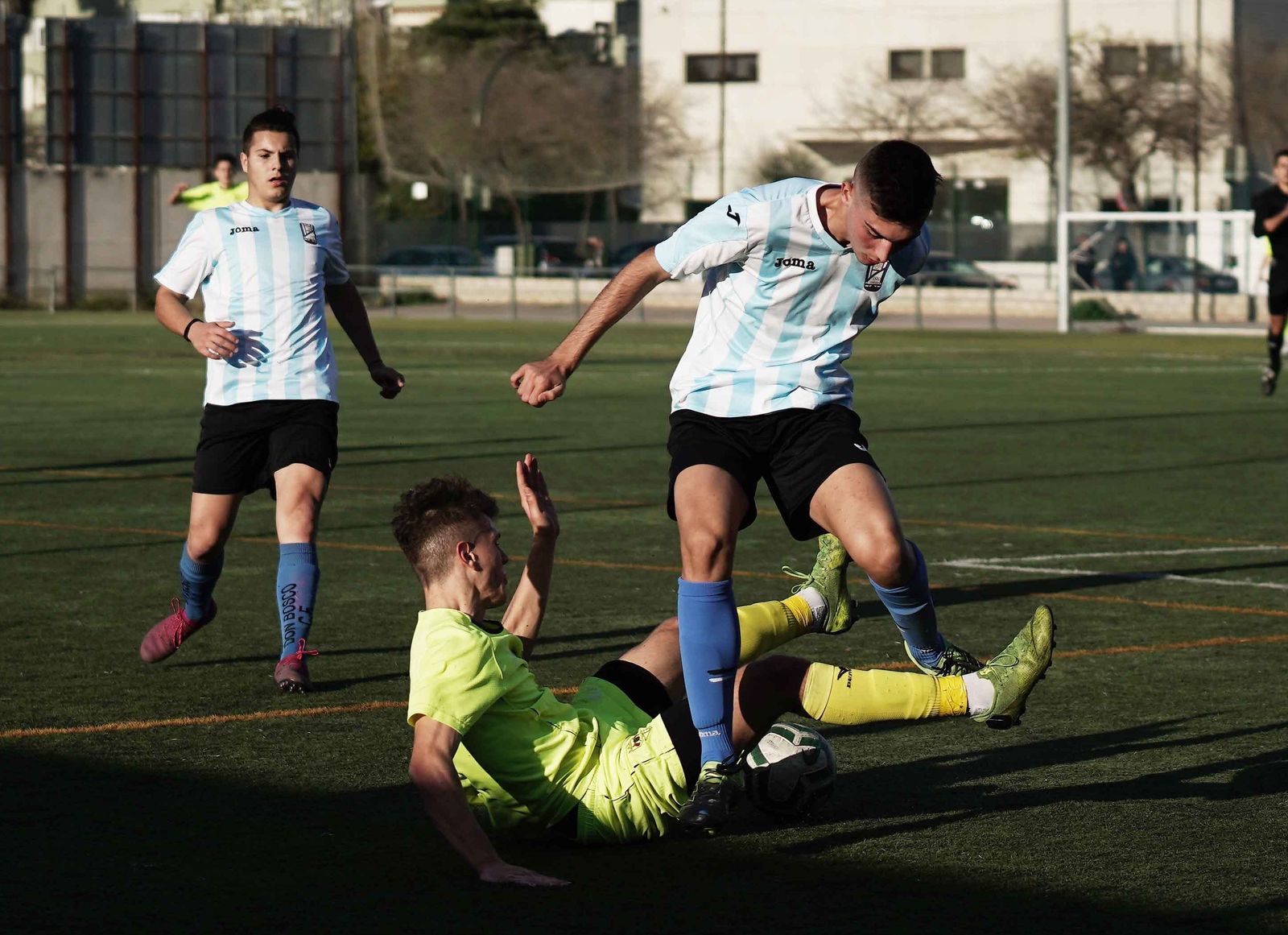 Un jugador del Séneca roba el balón desde el suelo a uno del Don Bosco.