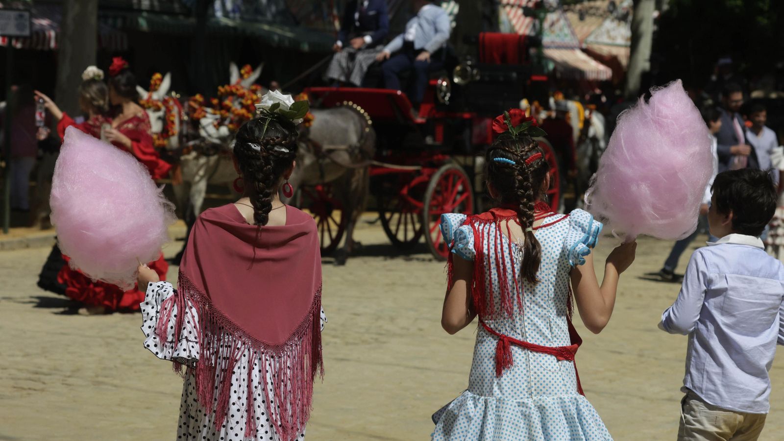 Dos niñas vestidas de flamenca con el clásico algodón de azúcar.