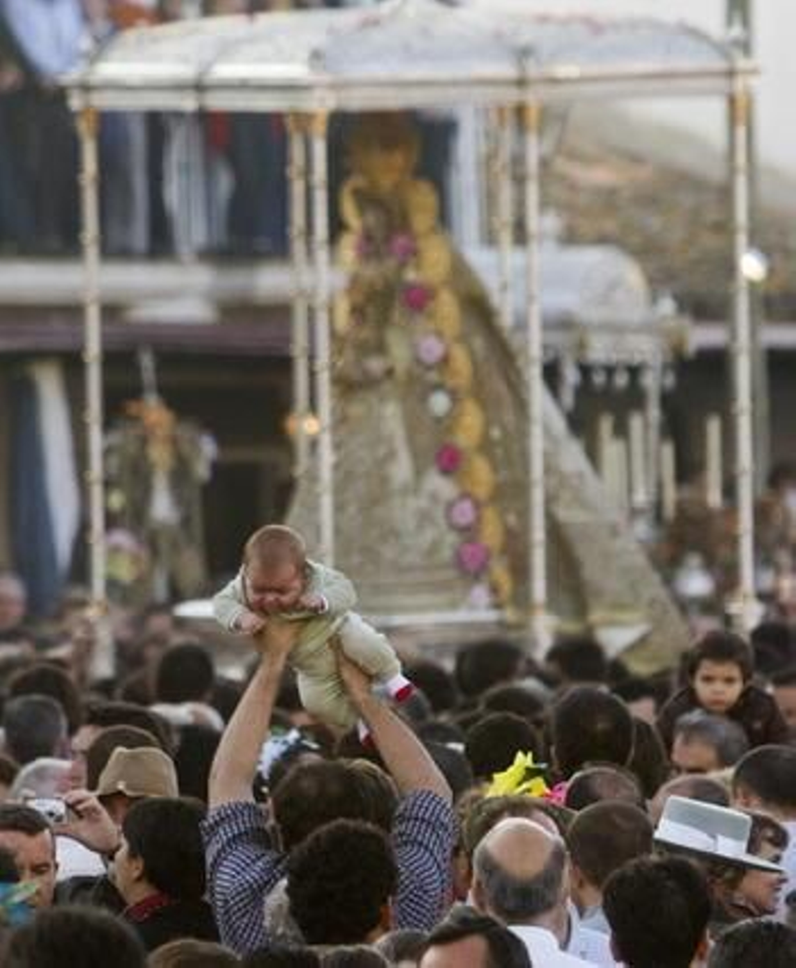 Un hombre se acerca a la virgen del Rocio llevando un bebe para posarlo en su manto.

Foto: Julián Pérez (EFE)