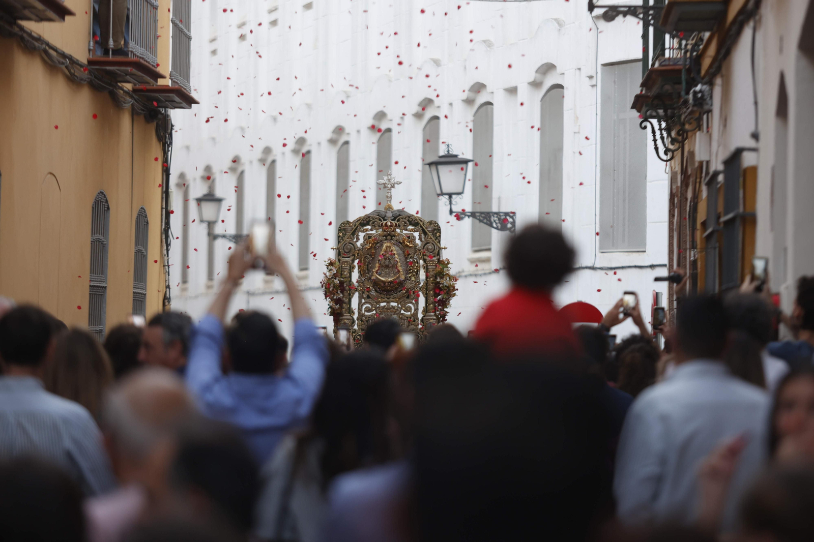 Los vecinos lanzan pétalos al simpecado de Triana en su traslado a Santa Ana.