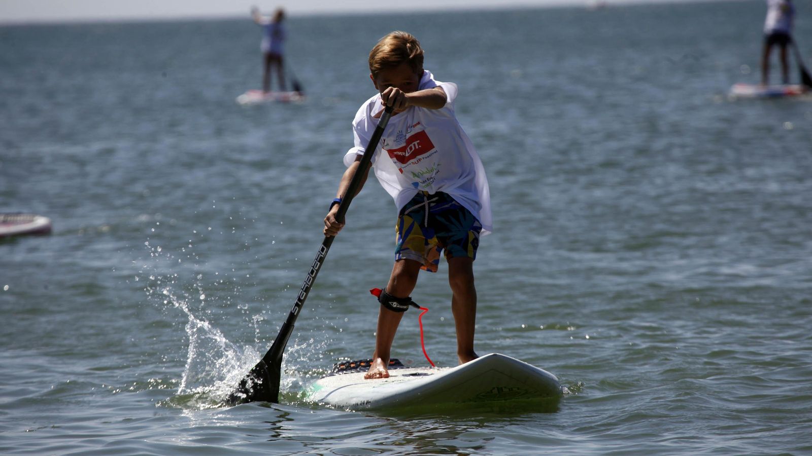 Un menor sobre su tabla de pádel surf en una playa onubense
