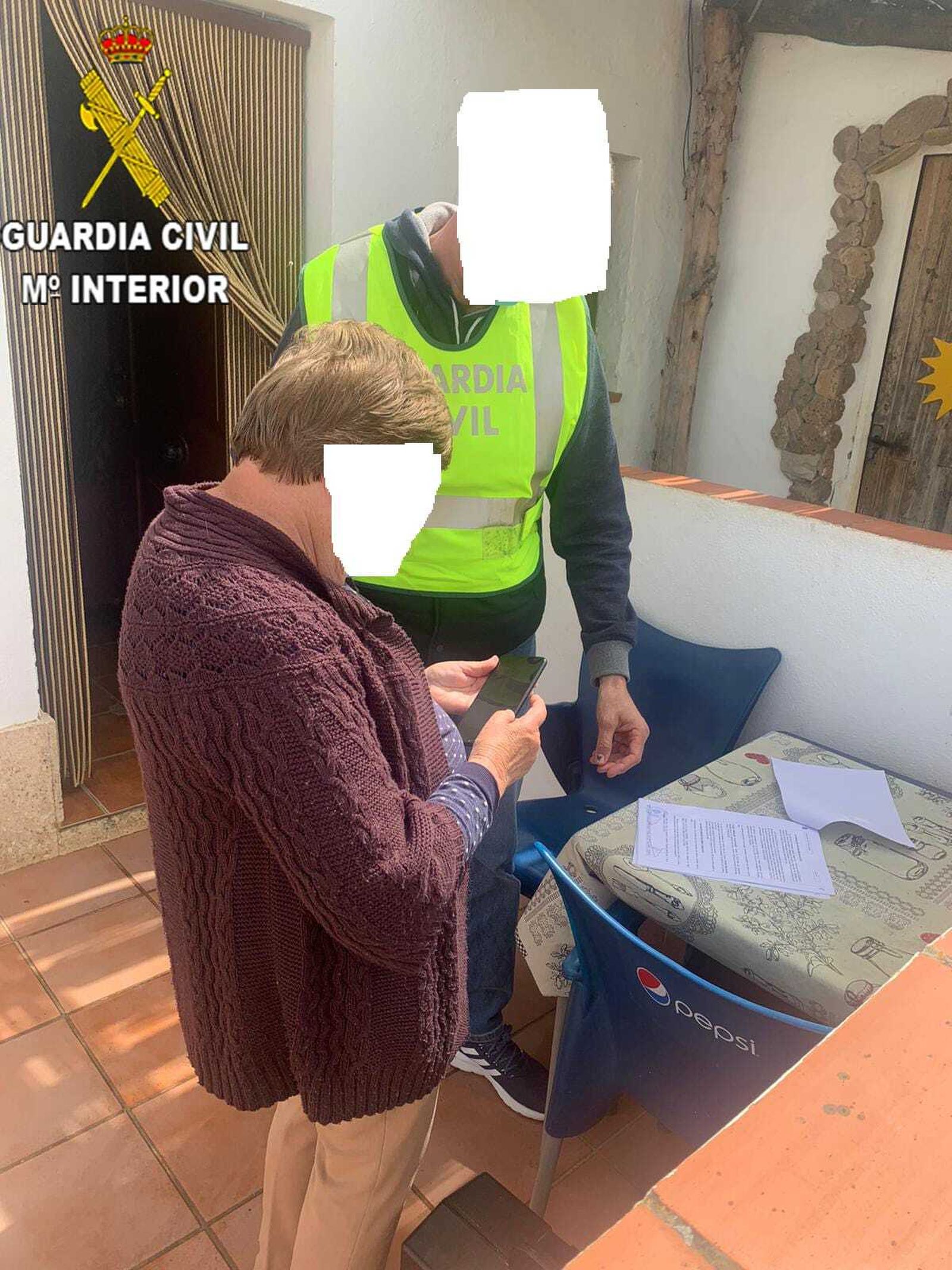La señora recibiendo su teléfono móvil de manos de un agente.