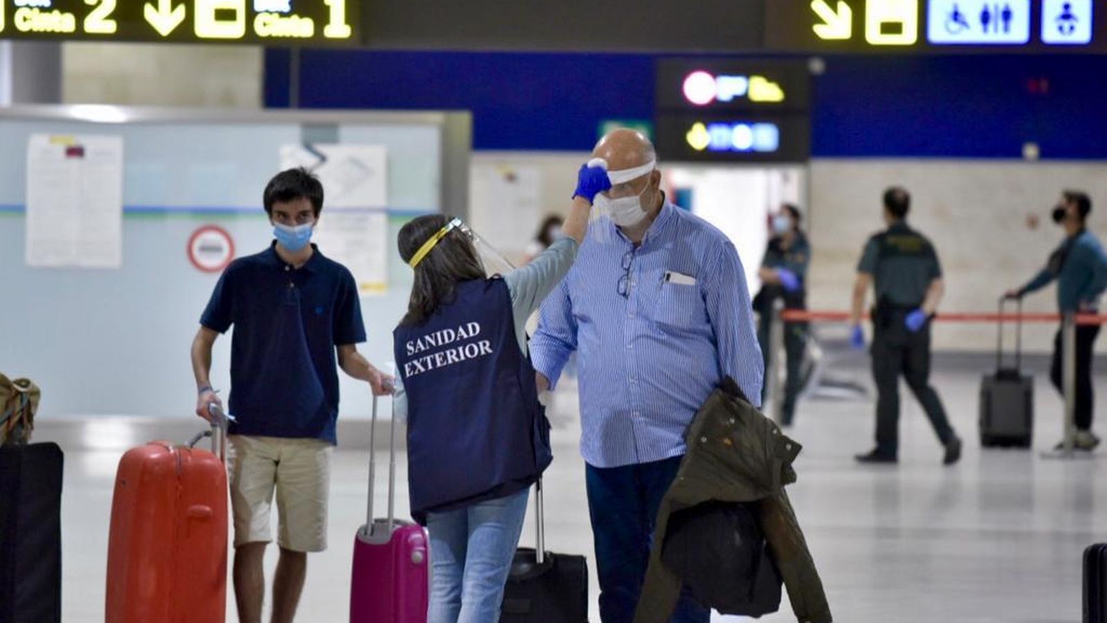 Toma de temperatura por parte del personal de Sanidad Exterior a los primeros pasajeros llegados del extranjero a Sevilla este viernes.