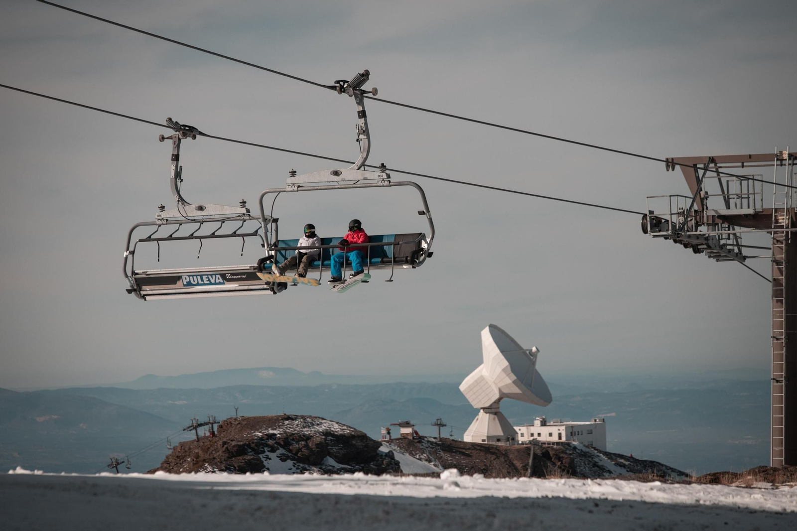 Dos riders con sus tablas de snow usan un remonte de Sierra Nevada este domingo