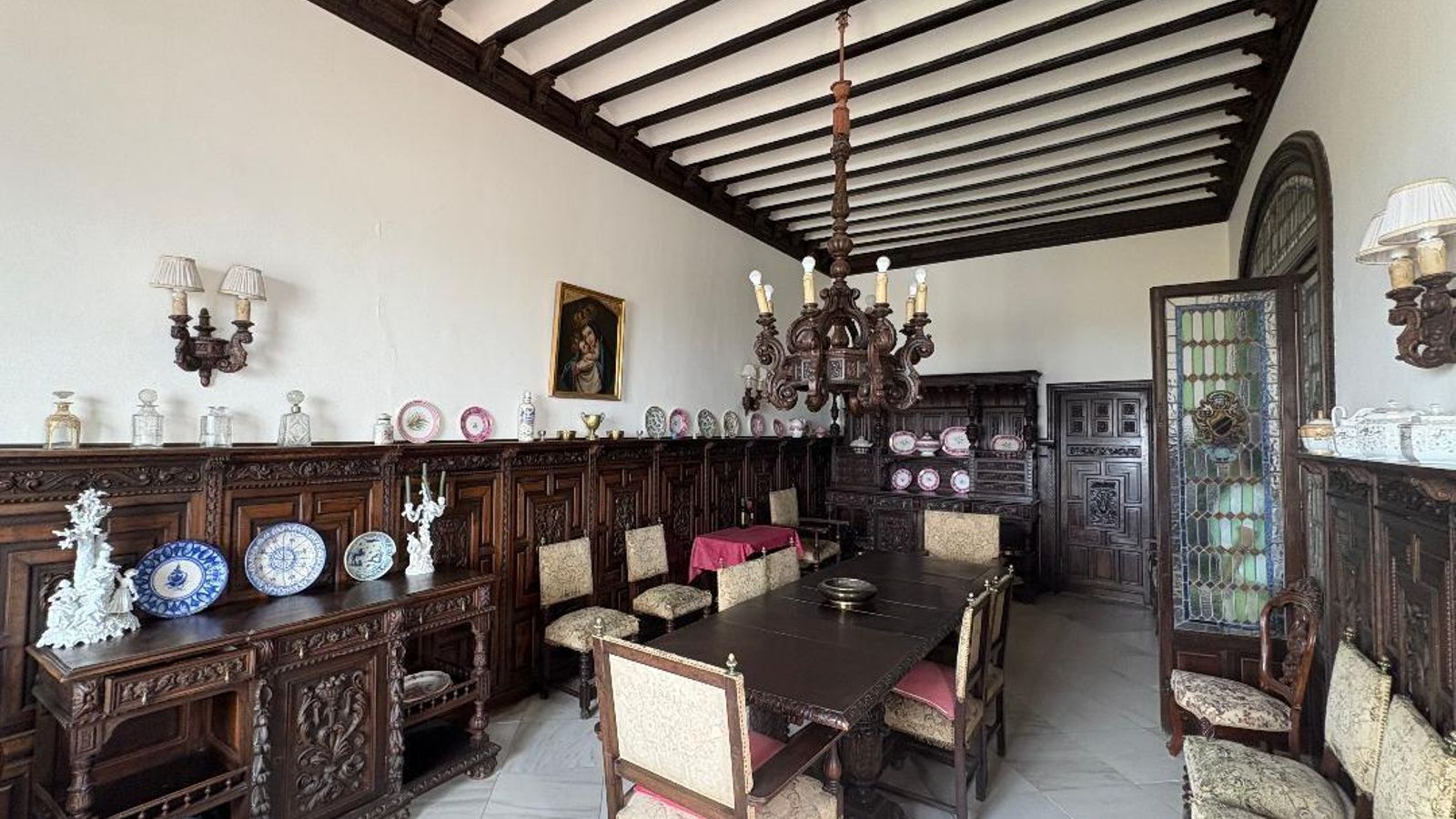 Comedor. Mobiliario de estilo español y puerta de vidriera emplomada.