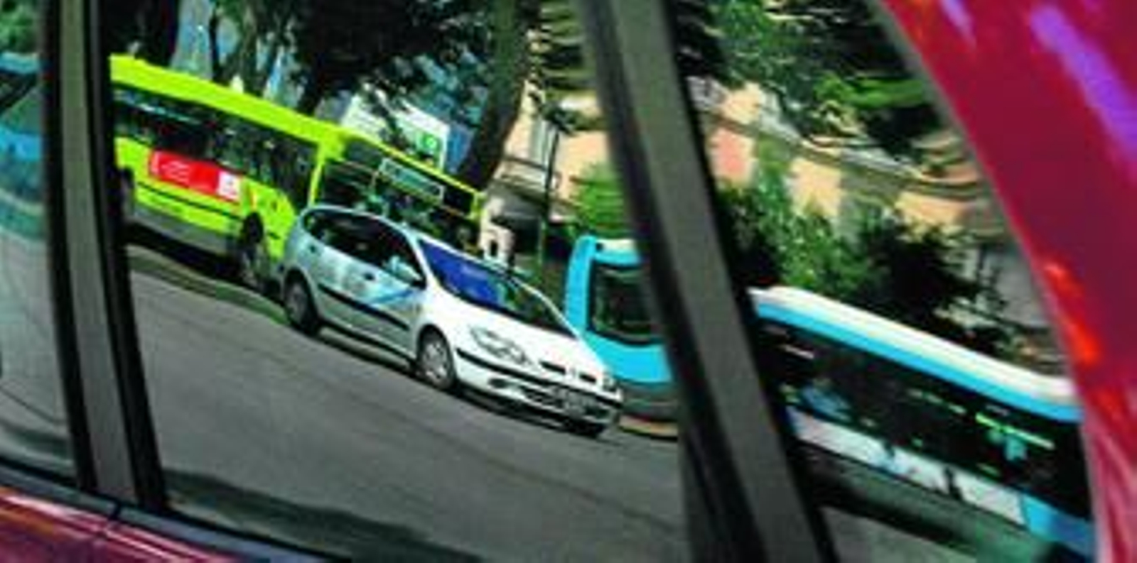 Un taxi reflejado en la ventana de un autobús de la EMT.