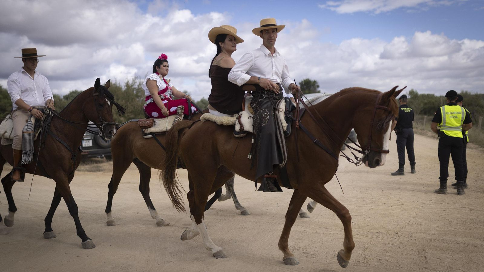 Romeros a caballo, en un cruce vigilado por la Guardia Civil.