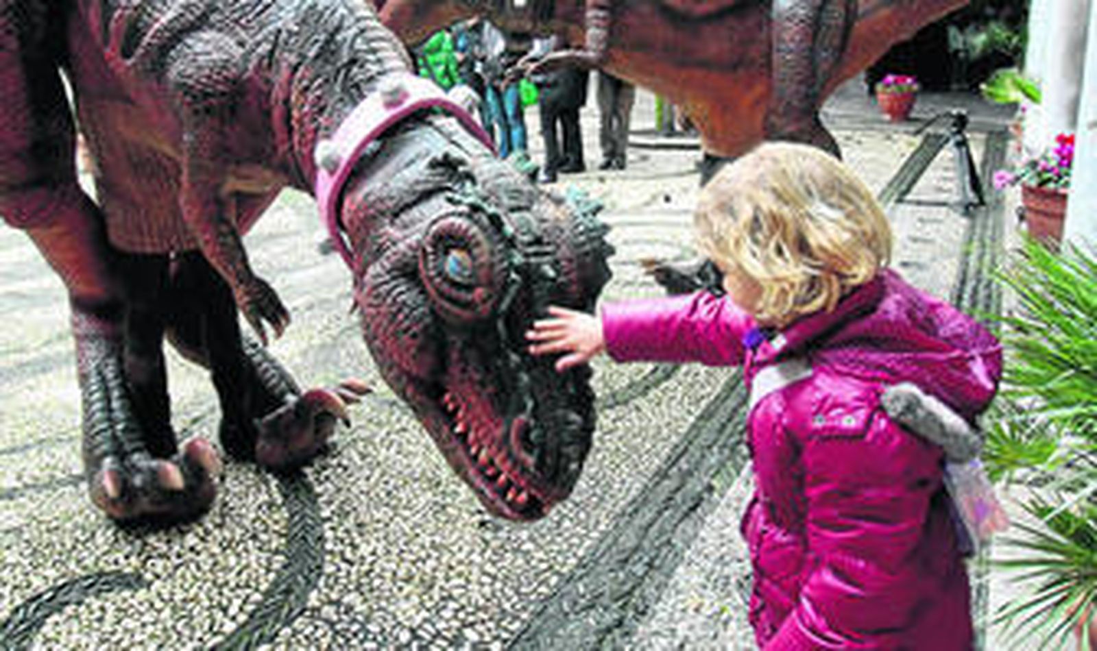 Una niña acaria uno de los dinosaurios en el interior del Ayuntamiento.