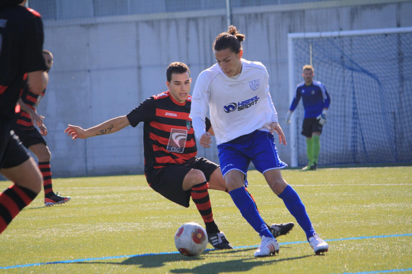Tore, en segundo plano vestido de rojo y negro, presiona a un jugador del Alcalá,