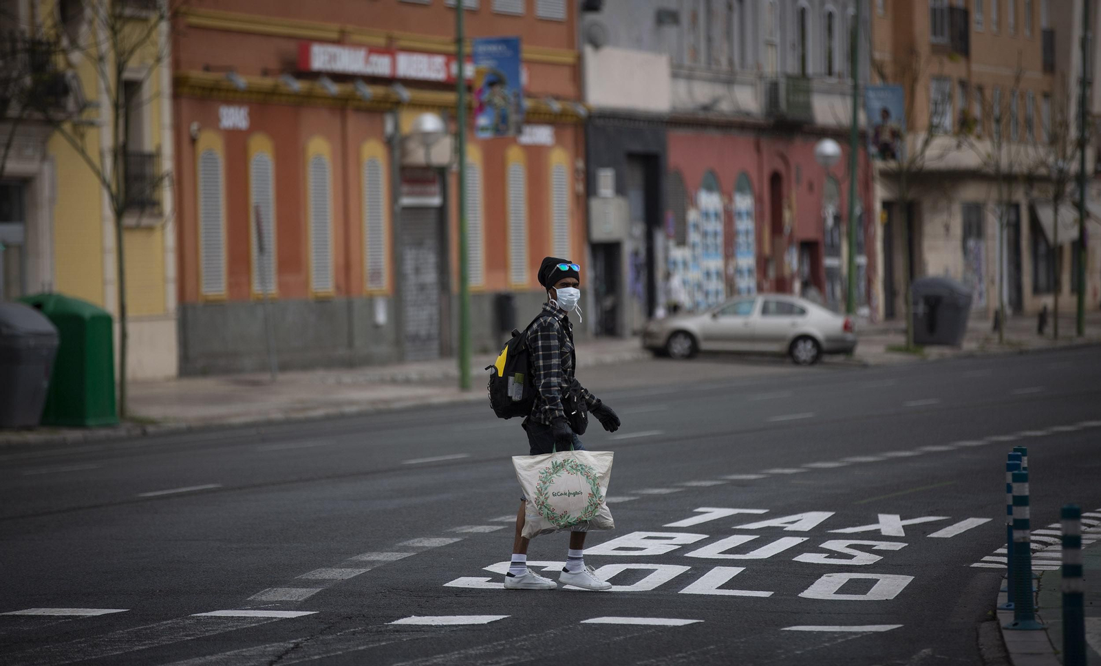 Un hombre con mascarillas en una solitaria Ronda Histórica en Sevilla.