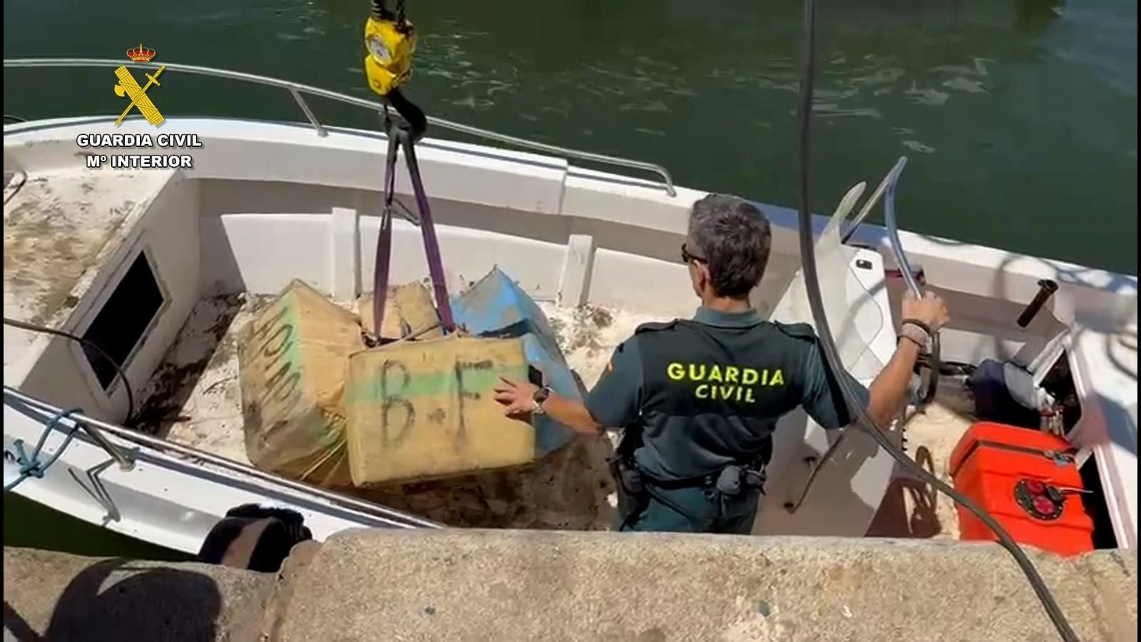 Un agente de la Guardia Civil junto a la droga incautada.