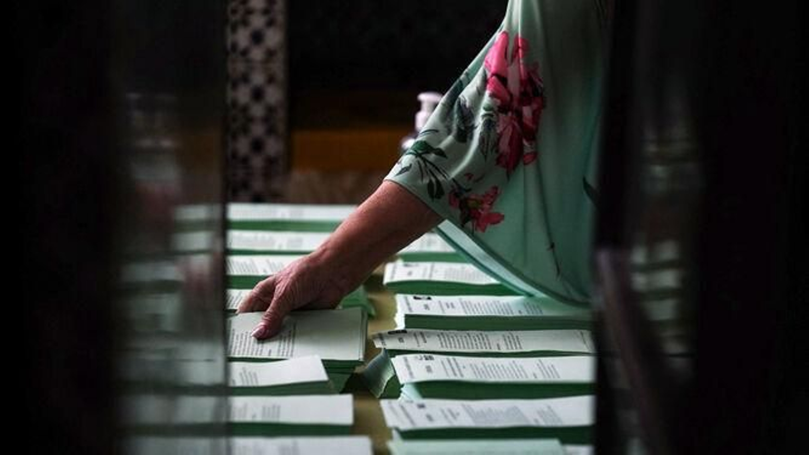 Una mujer tanteando varias papeletas en unas elecciones