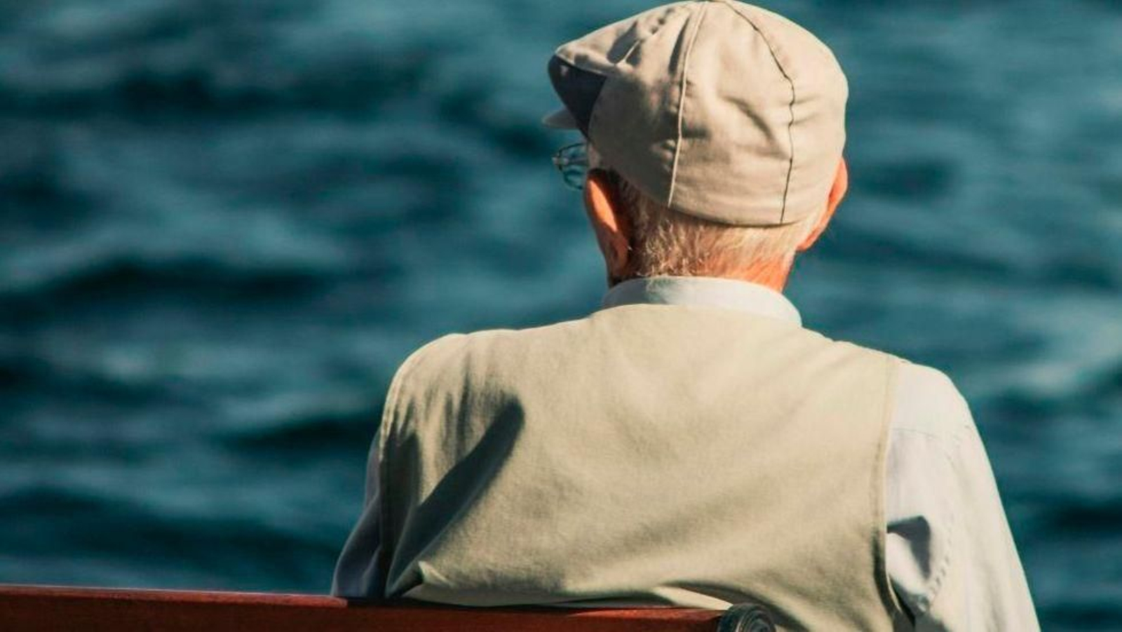 Una persona mayor sentada en un banco.