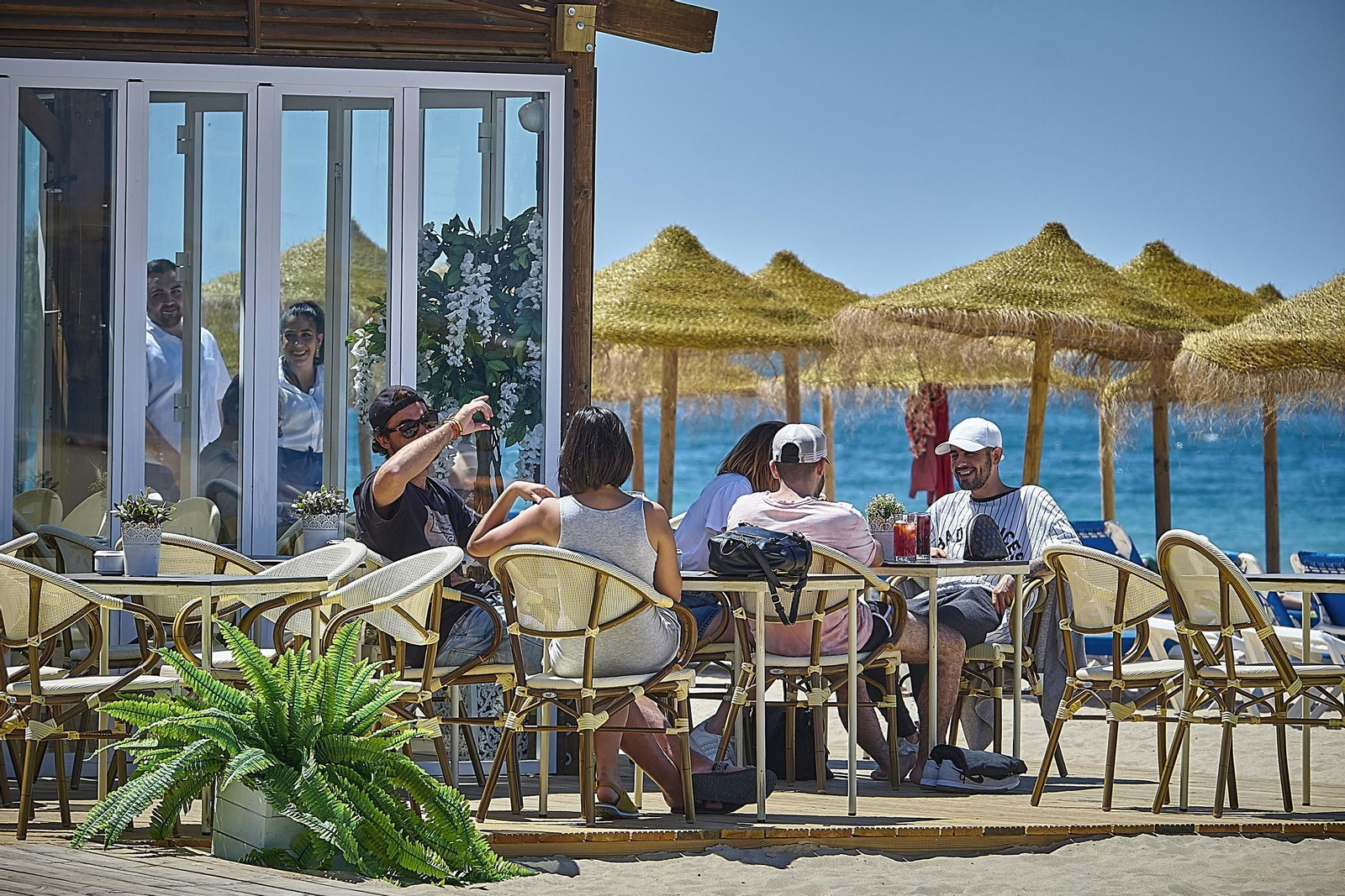 Unos clientes disfrutan de la terraza de un chiringuito.
