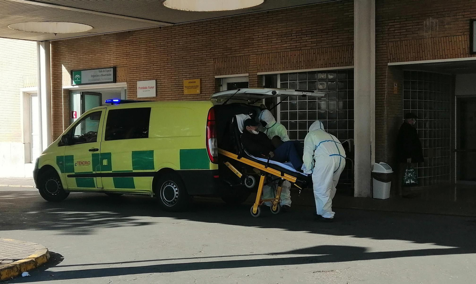 Dos sanitarios bajan en camilla a un paciente a las puertas de Urgencias del Hospital Virgen del Rocío.