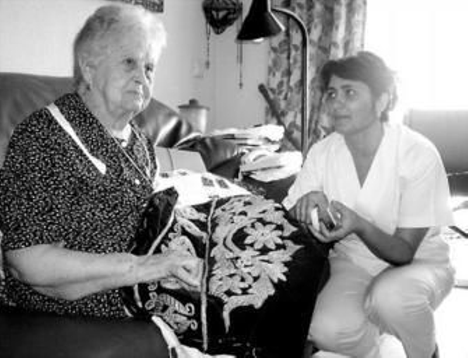 Dulce borda un manto ante la mirada de Elisa, su cuidadora.