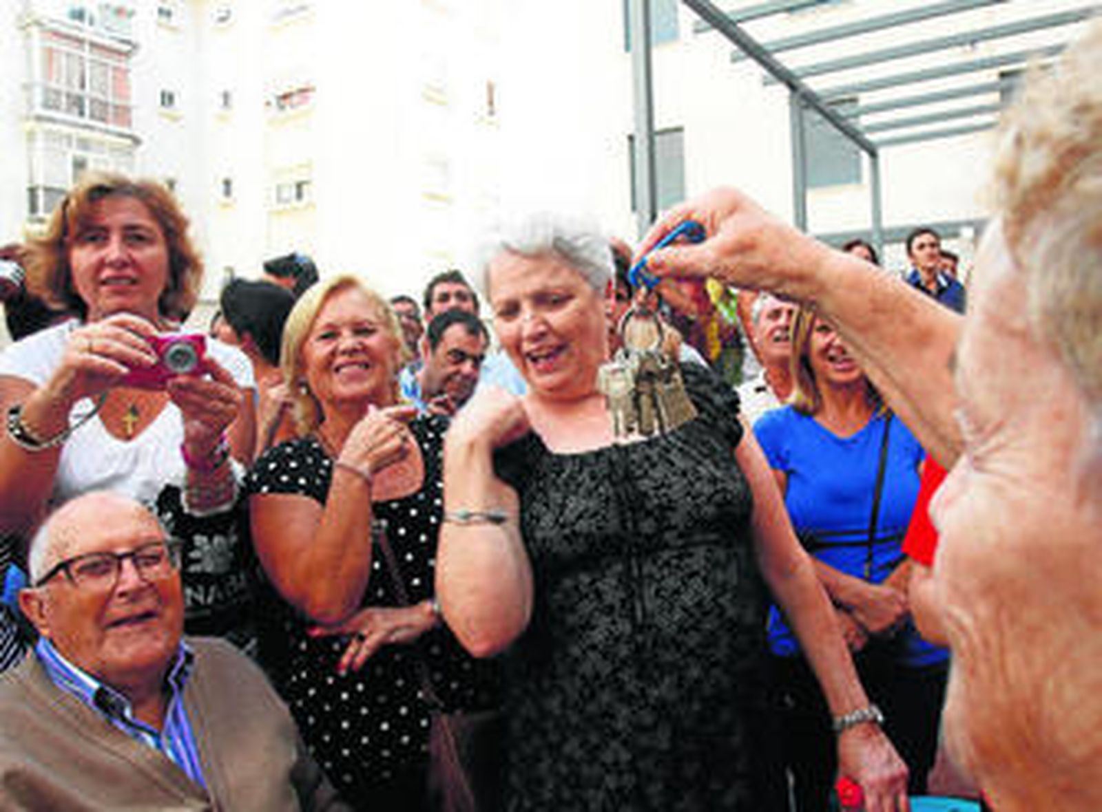 Una mujer muestra las llaves de su nueva casa a sus vecinos.