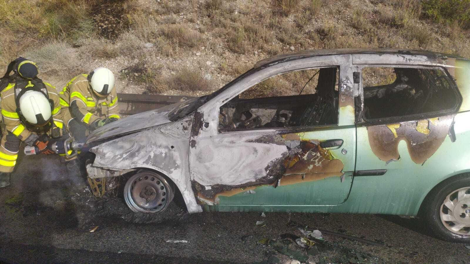 Los bomberos, tras la extinción del fuego del vehículo.