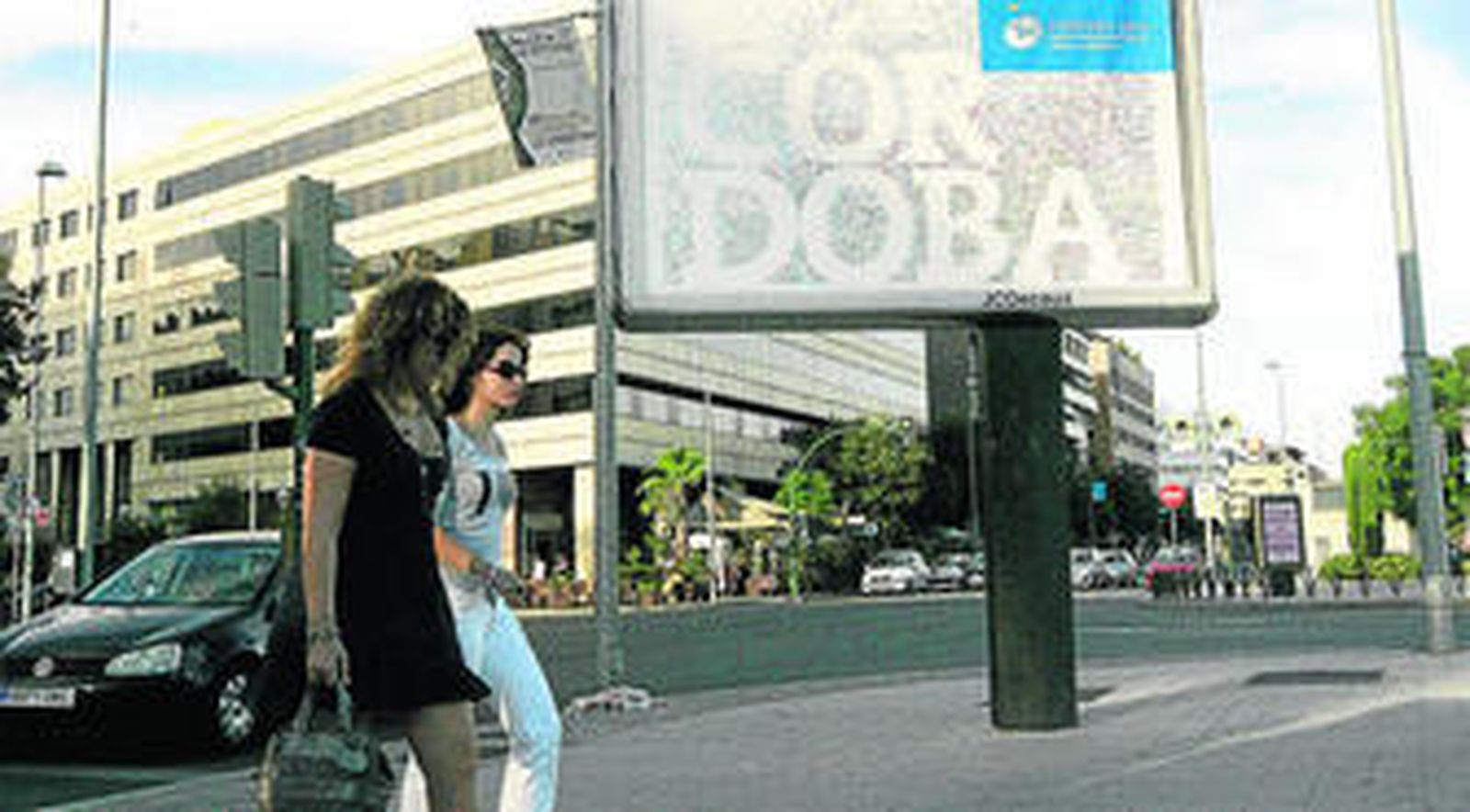 Dos ciudadanas pasan delante de uno de los carteles que anuncian la candidatura de Córdoba.