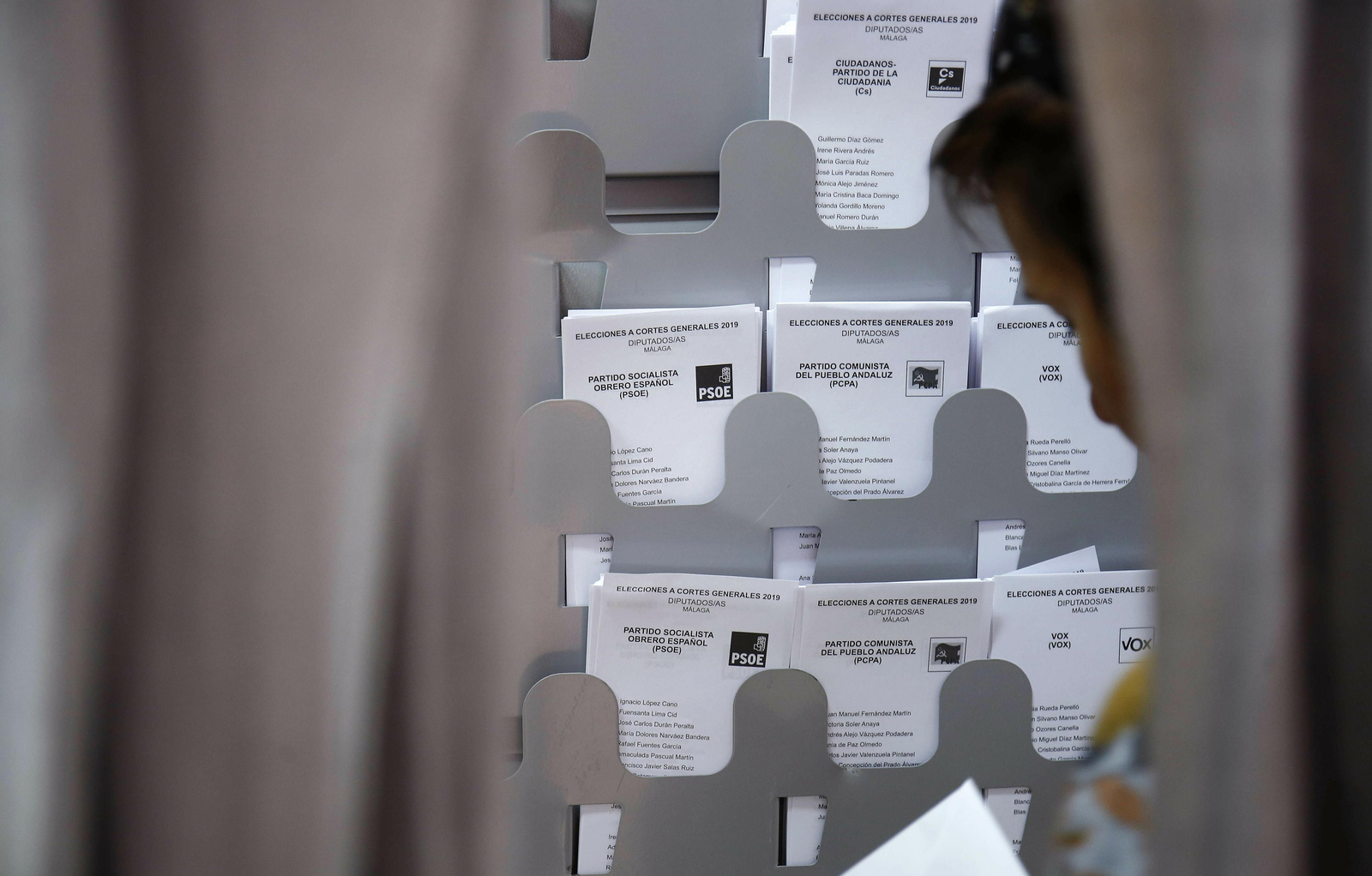 Una persona coge un voto en un colegio electoral.