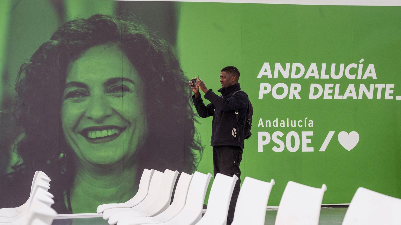 Un periodista saca fotos del Plenario ante una imagen con la futura líder del partido en Andalucía, María Jesús Montero