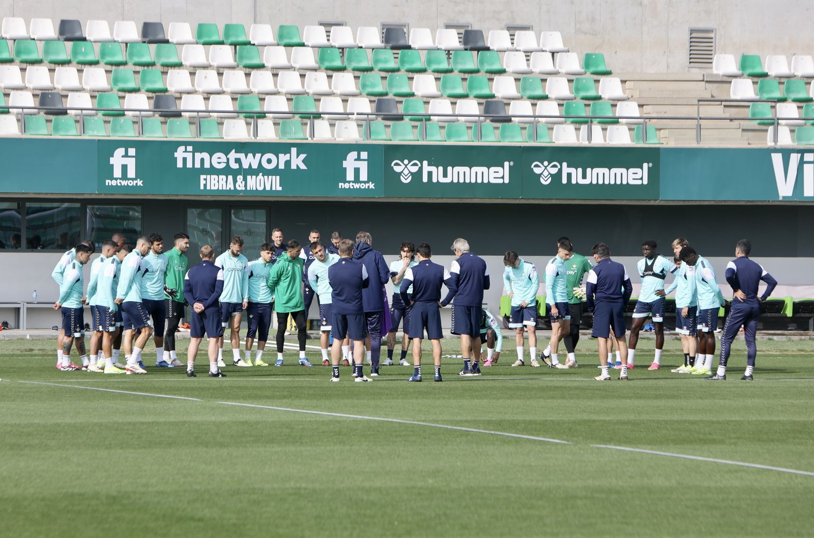 Los jugadores del Betis siguen con atención la charla de Manuel Pellegrini previa al comienzo del entrenamiento de ayer en el campo principal de la ciudad deportiva.