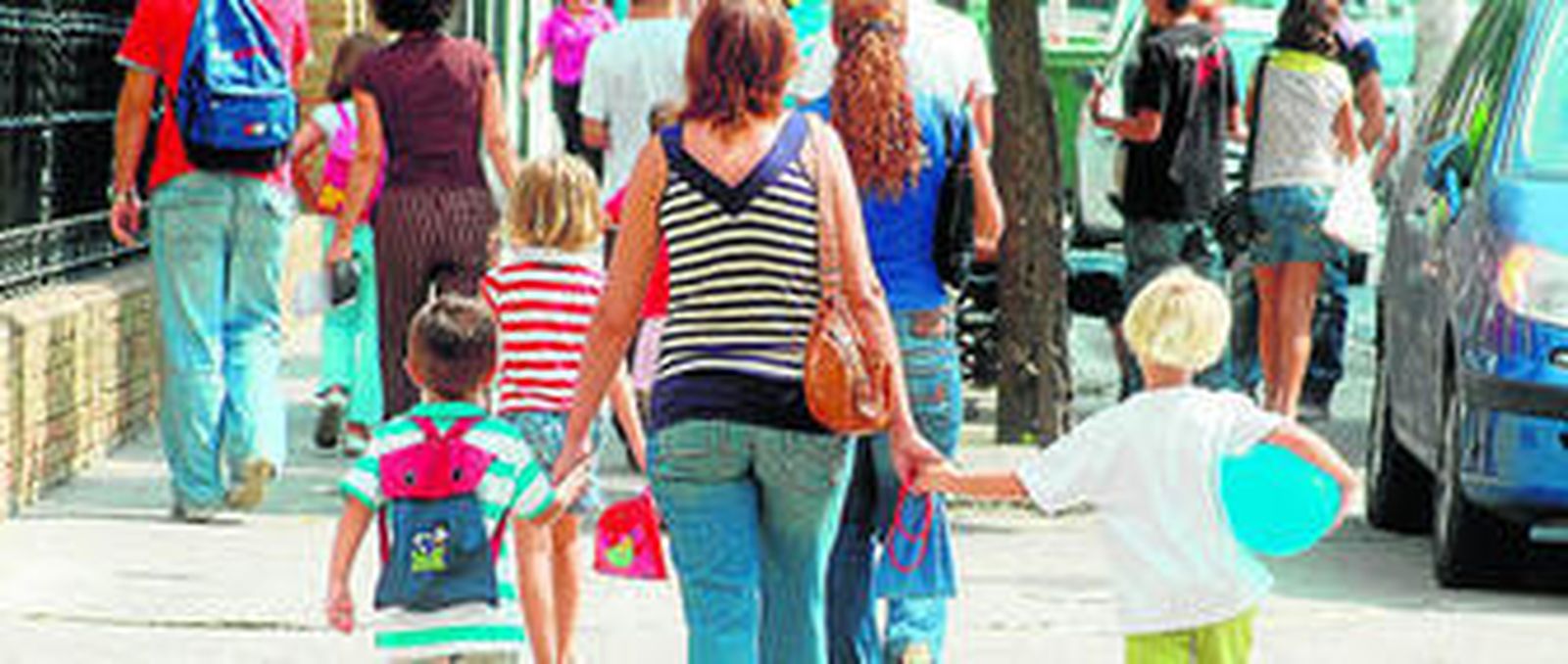 Niños con sus padres camino del colegio.