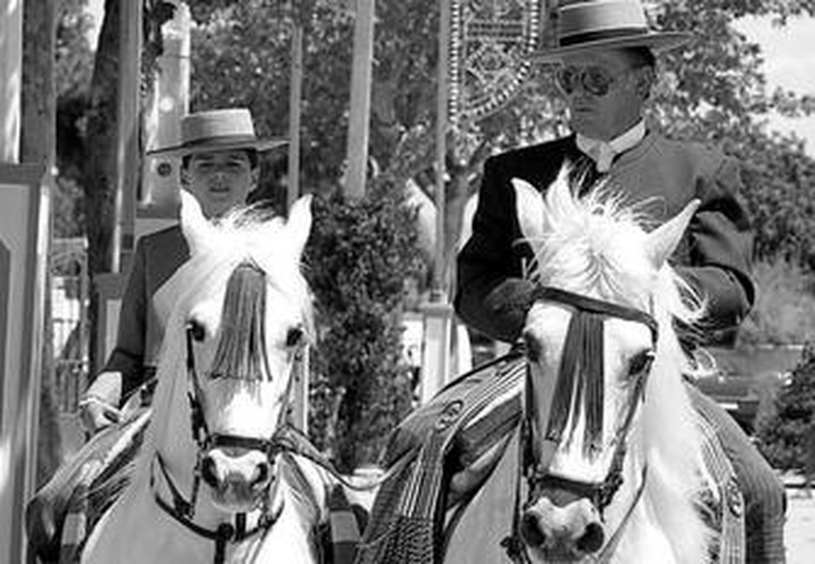 Dos jinetes pasean por el recinto ferial en una imagen de la pasada edición. A la derecha, el cartel que anuncia el concurso ecuestre.