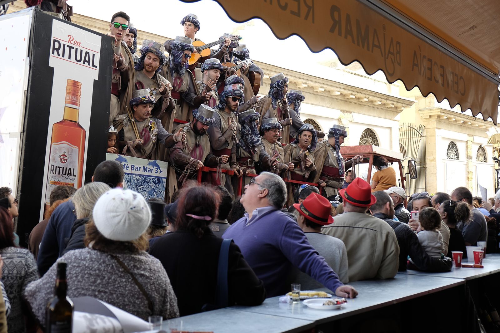 Un coro canta junto a la barra de un negocio hostelero.